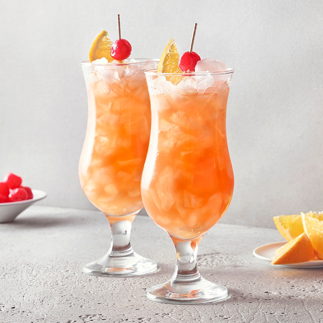Gläser mit orangefarbenem Getränk voller Eiswürfel, garniert mit einer Zitronenspalte.