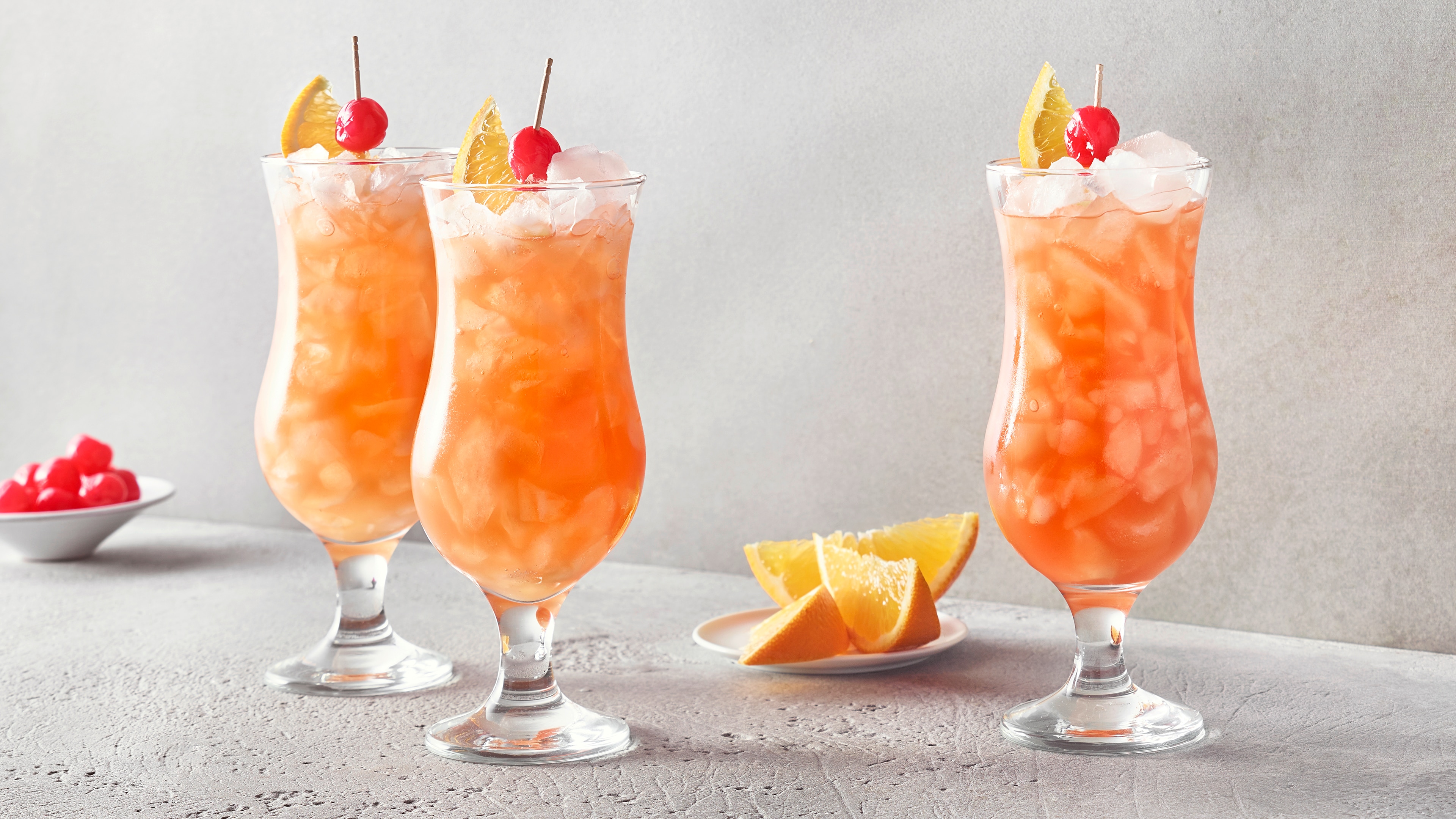 Gläser mit orangefarbenem Getränk voller Eiswürfel, garniert mit einer Zitronenspalte.