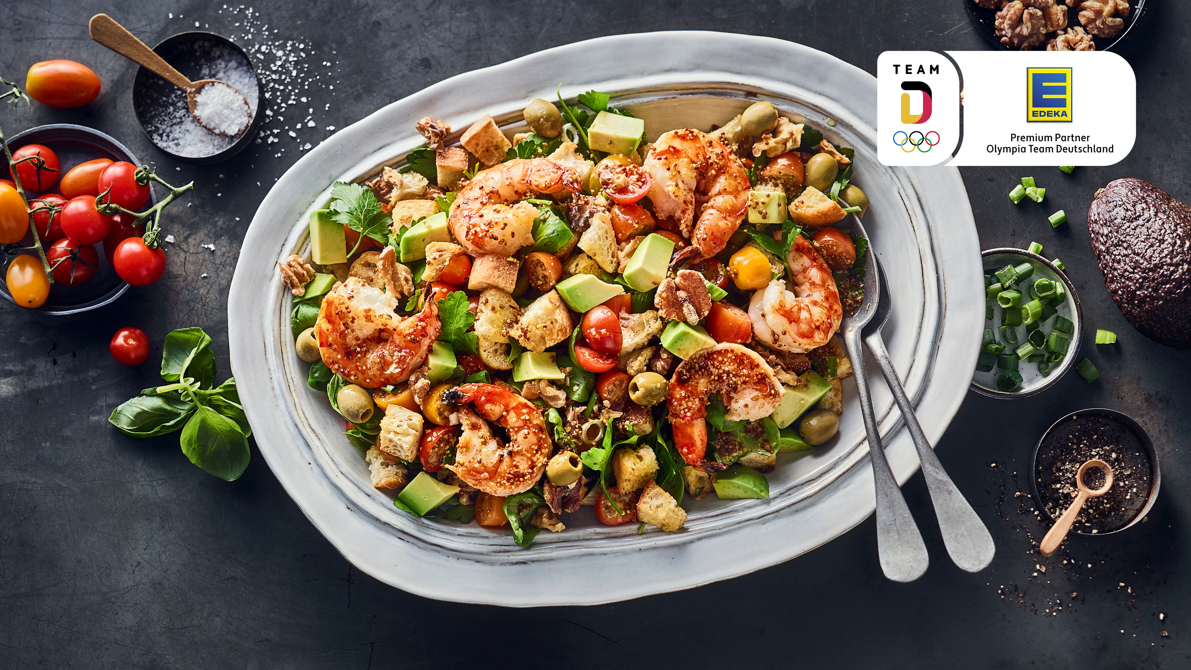 Rezept für italienischen Brotsalat mit Garnelen Großer Teller mit Salat aus Avocado, Brotwürfeln, Tomaten und Garnelen.