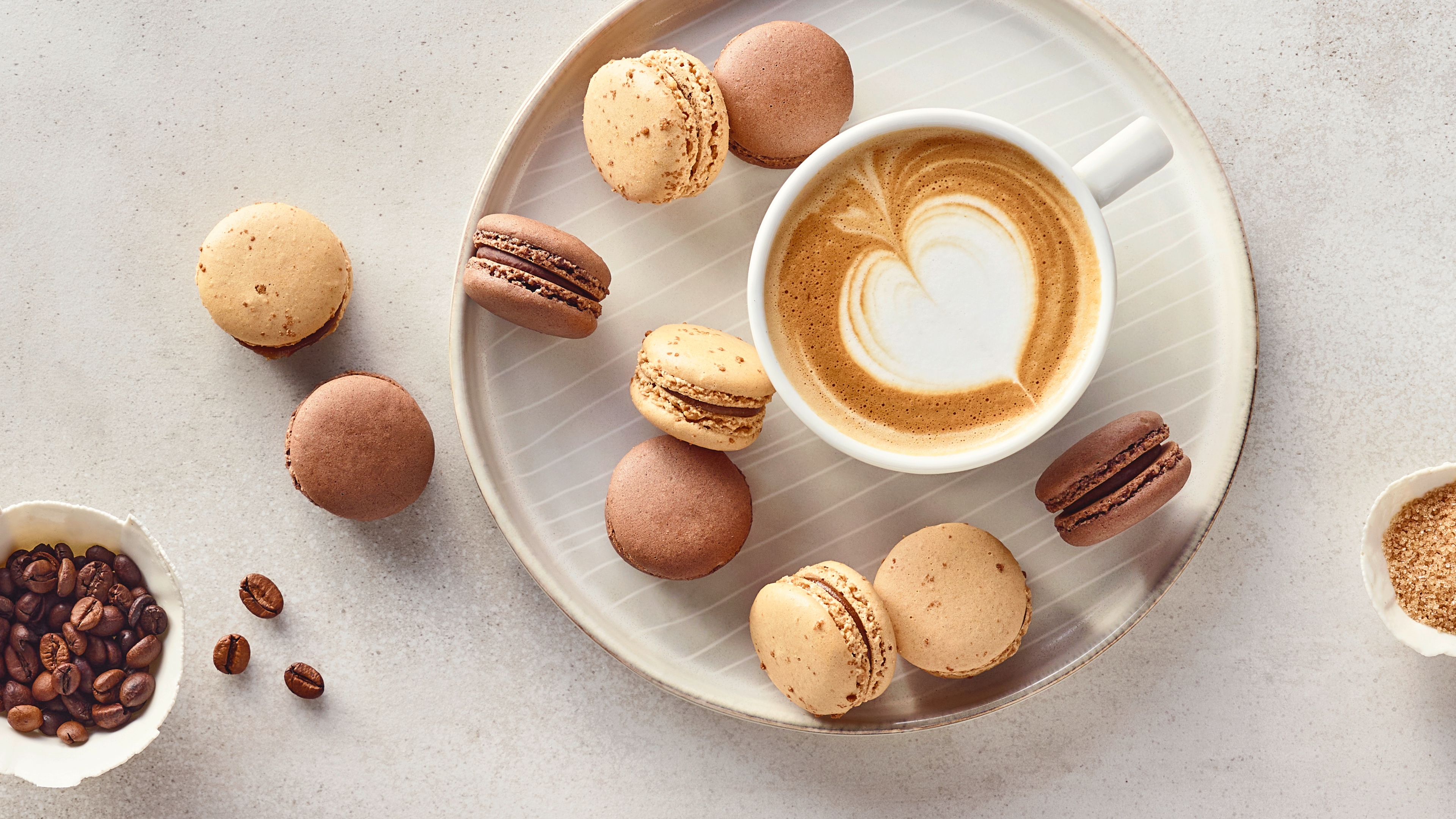 Ein Teller mit braunen und beigen Macarons und einer Tasse Kaffee