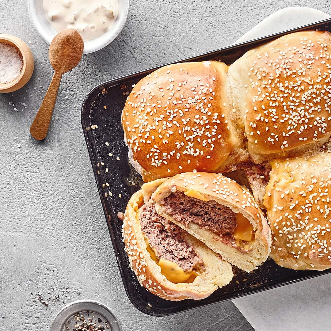 Vier in Teig eingebackene Burger, goldbraun gebacken, gefüllt mit Rindfleisch und geschmolzenem Käse.