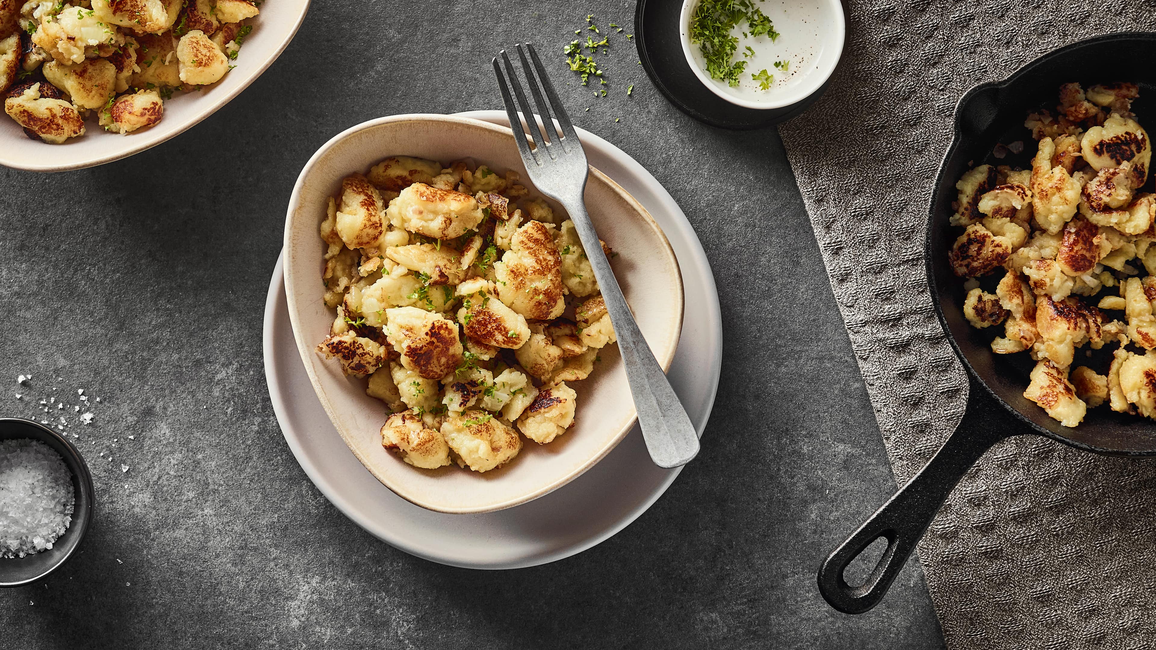 Rezept für Kartoffelschmarrn Eine Schale mit knusprig gebratenen kleinen Kartoffelteigstückchen, garniert mit gehackter Petersilie