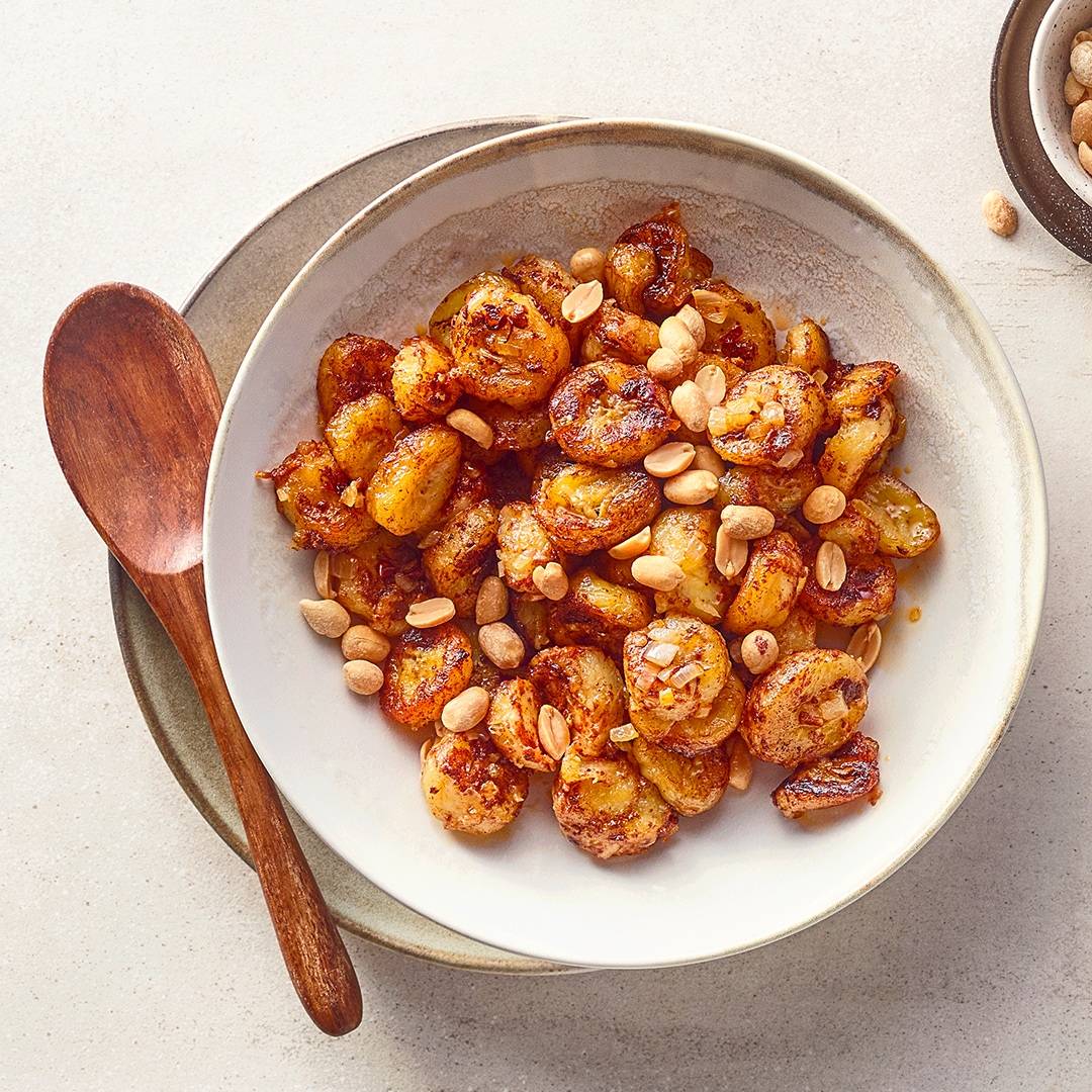 Tiefer Teller mit angebratenen gewürzten Kochbananen-Stücken