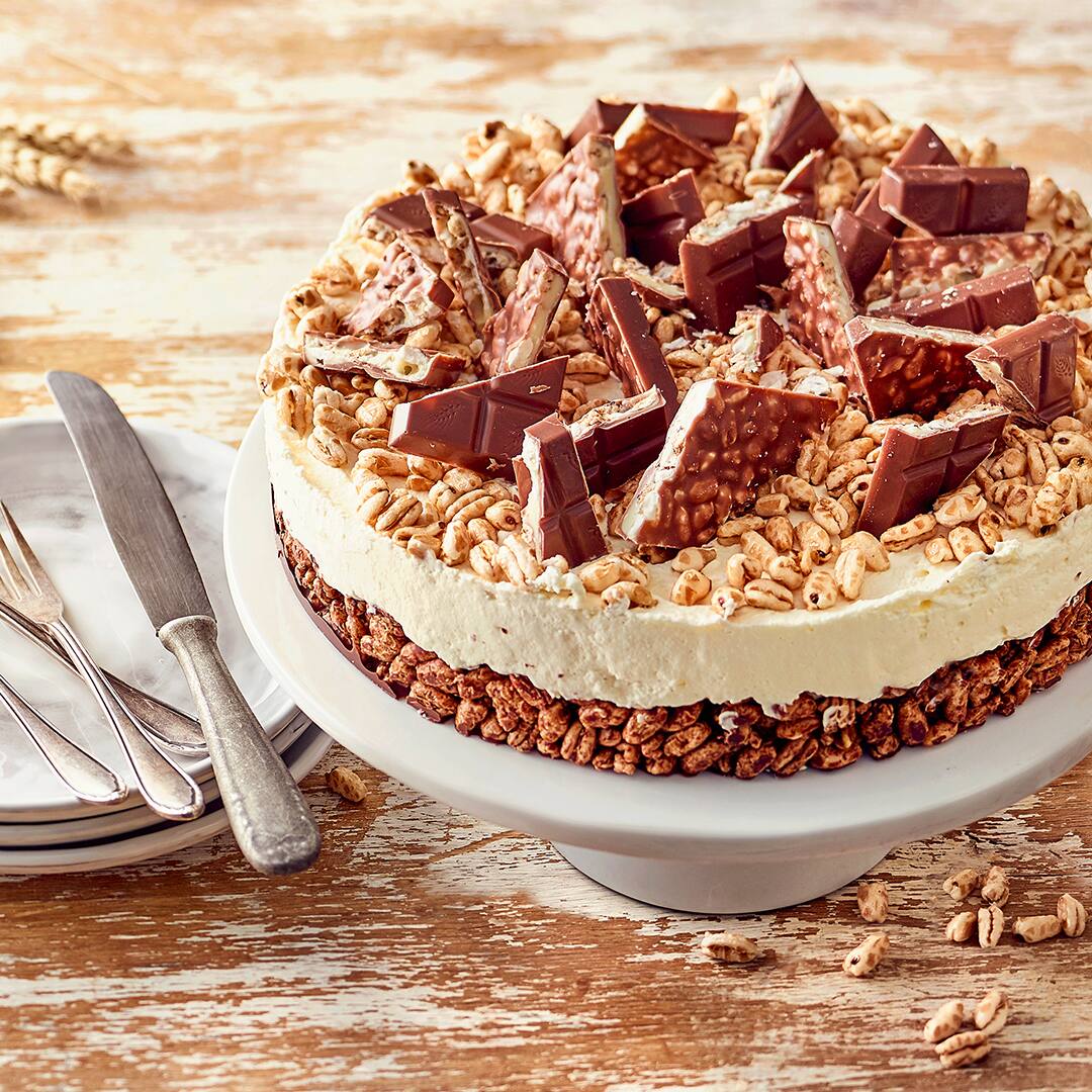 Ein Kuchen mit gepufftem Weizen-Boden, heller Creme und getoppt mit Kinder-Country-Stücken, auf einer Torten-Etagere