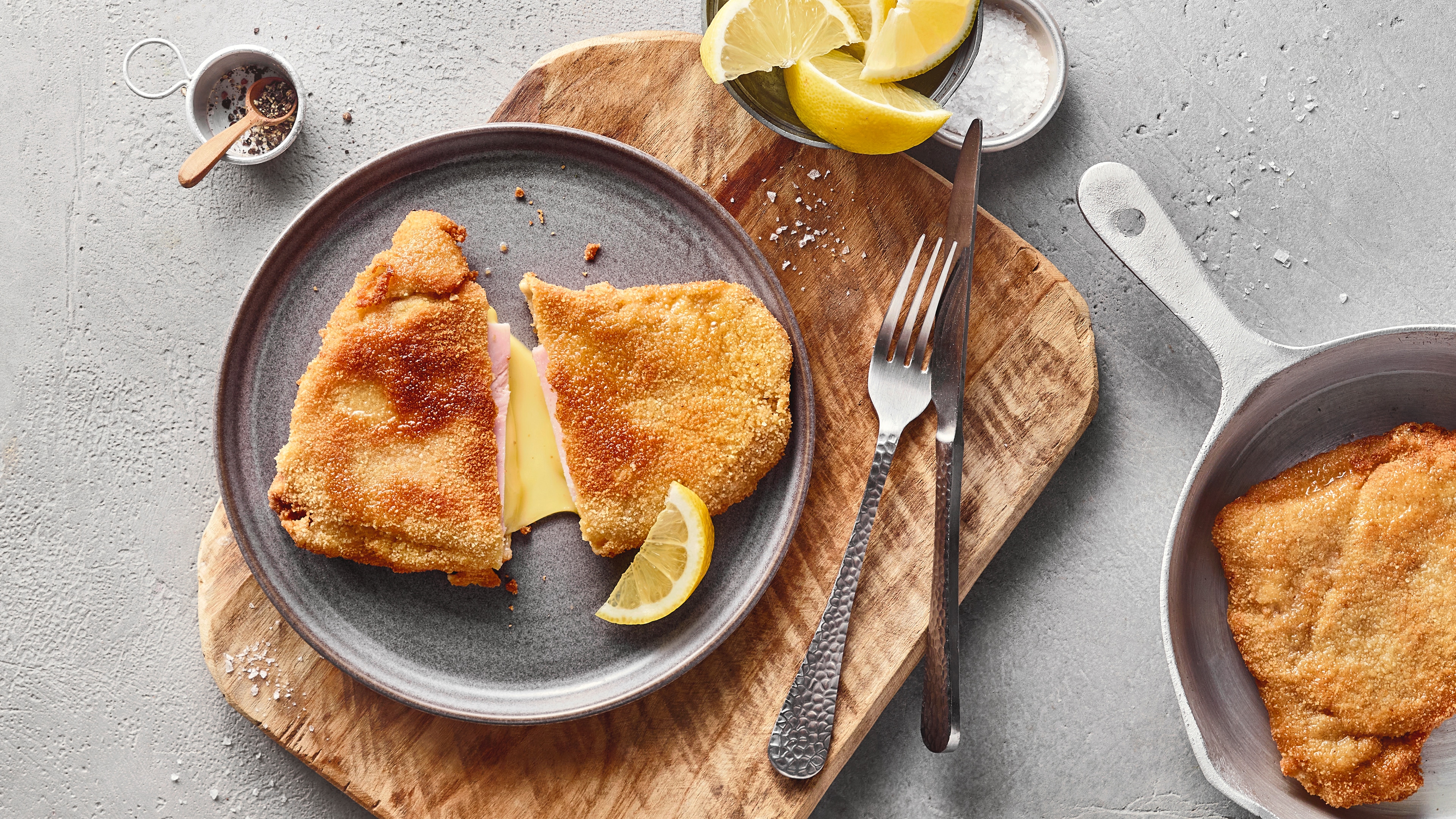 Ein Teller mit einem panierten Schnitzel, gefüllt mit Käse und Schinken, garniert mit einer Zitrone.