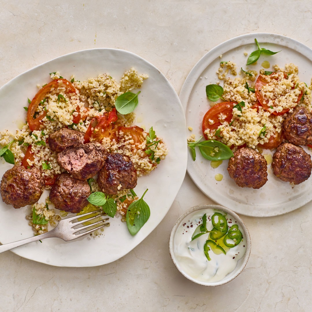 Zwei Teller mit Hackbällchen, Bulgur und Tomaten