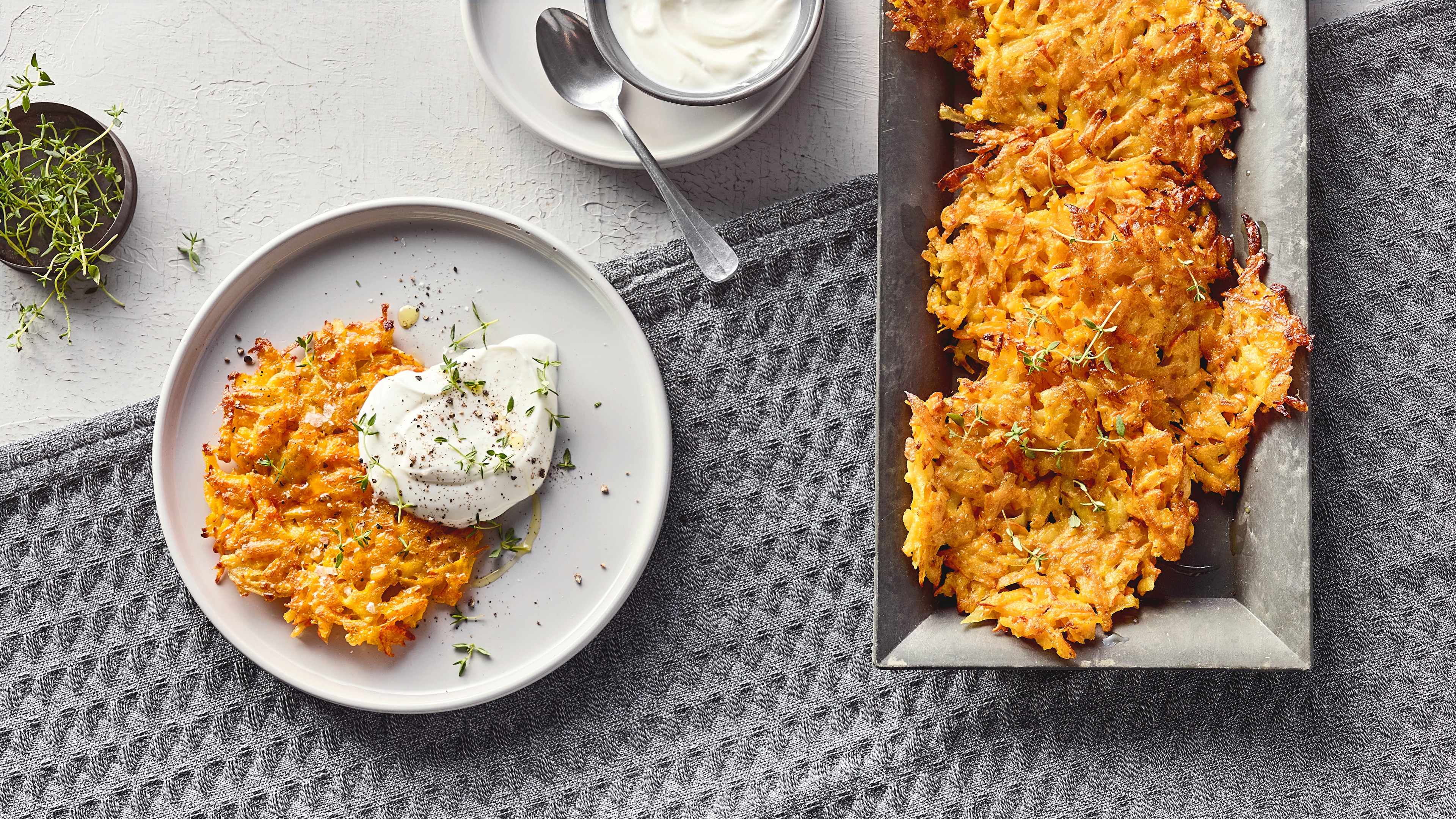 Rezept für Kürbis-Rösti Knuspriger, gelbgold gebratener Taler mit einem großen Klecks cremigem weißen Dip, auf einem runden Teller