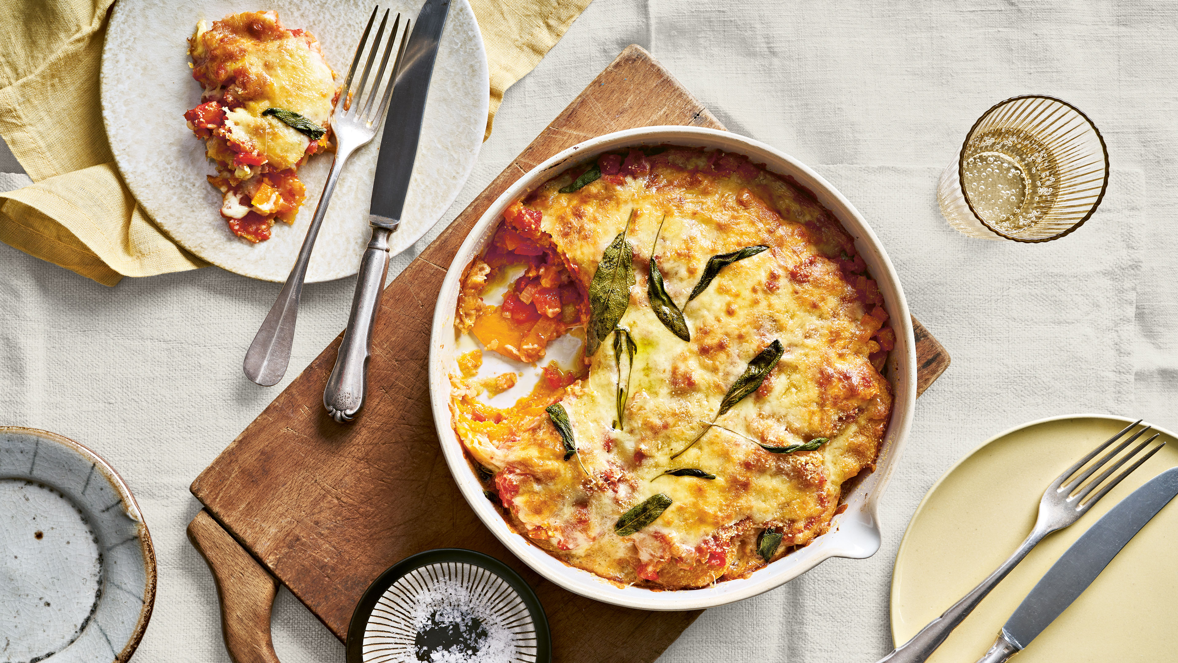 Runde Auflaufform mit Kürbisscheiben, roter Soße und Käse überbacken
