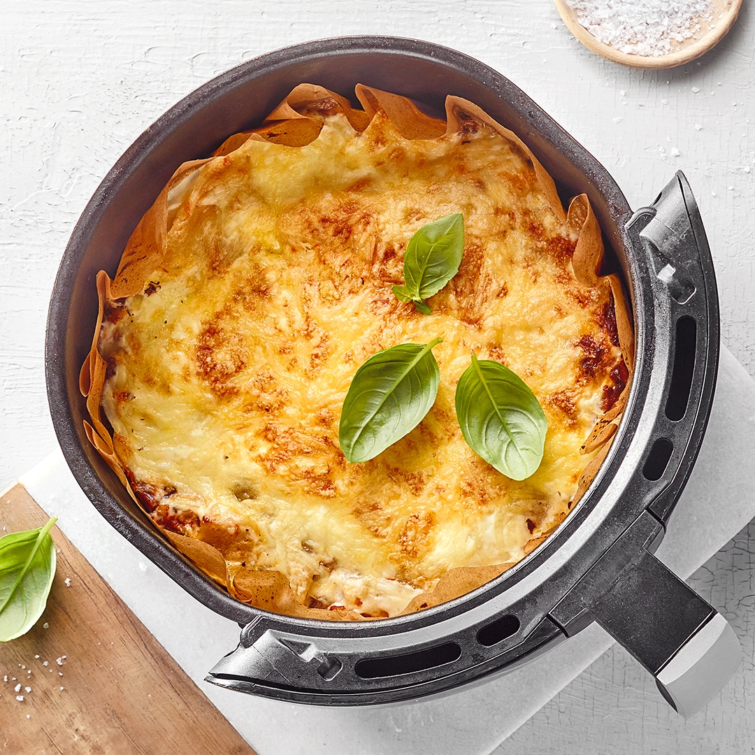 Airfryerkorb mit Lasagneplatten, Hackfleisch und Käse.