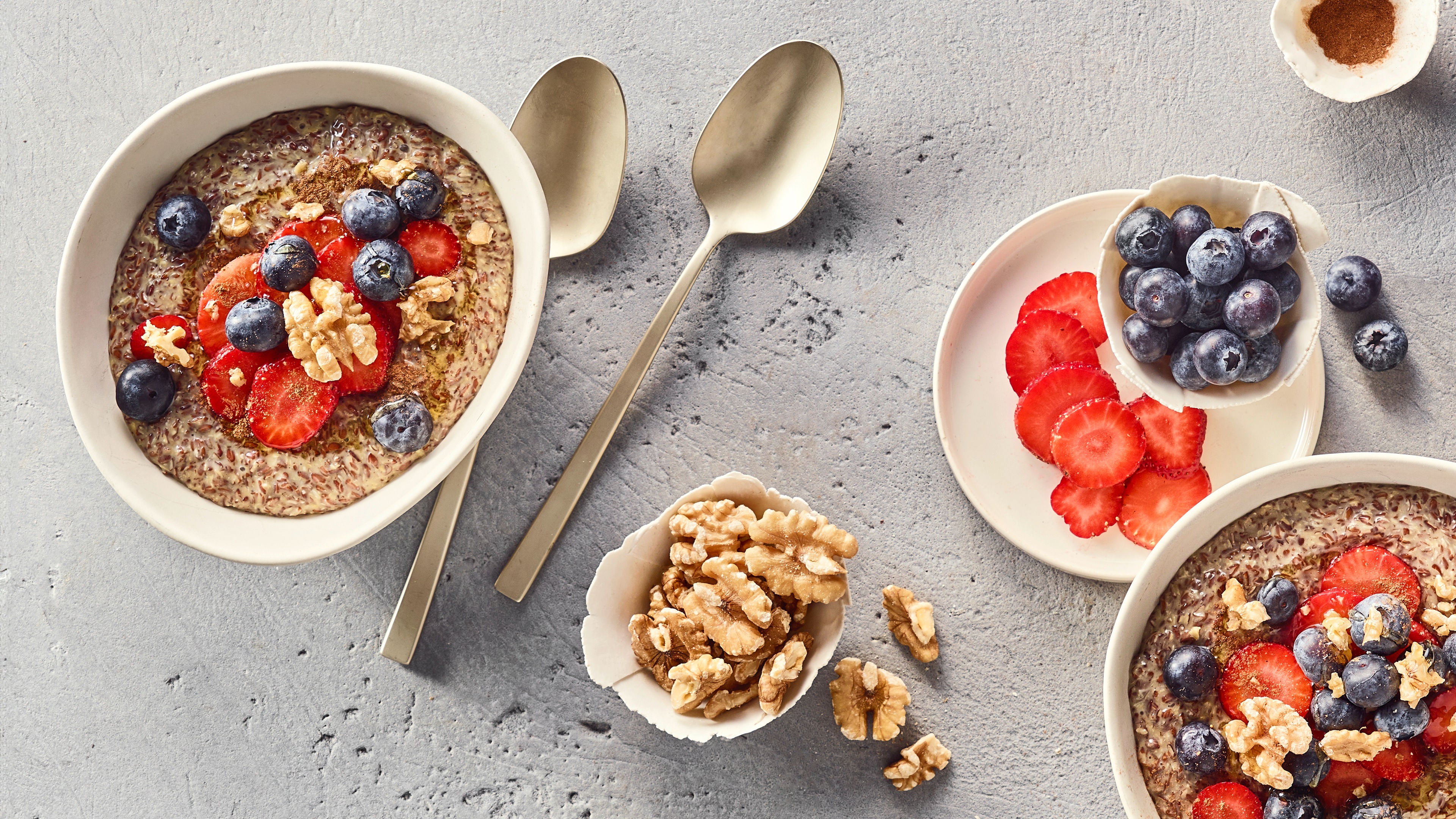 Eine Schüssel mit Leinsamen-Pudding, darauf rote Erdbeerscheiben, ganze blaue Heidelbeeren und grobe Stücke heller Walnüsse.