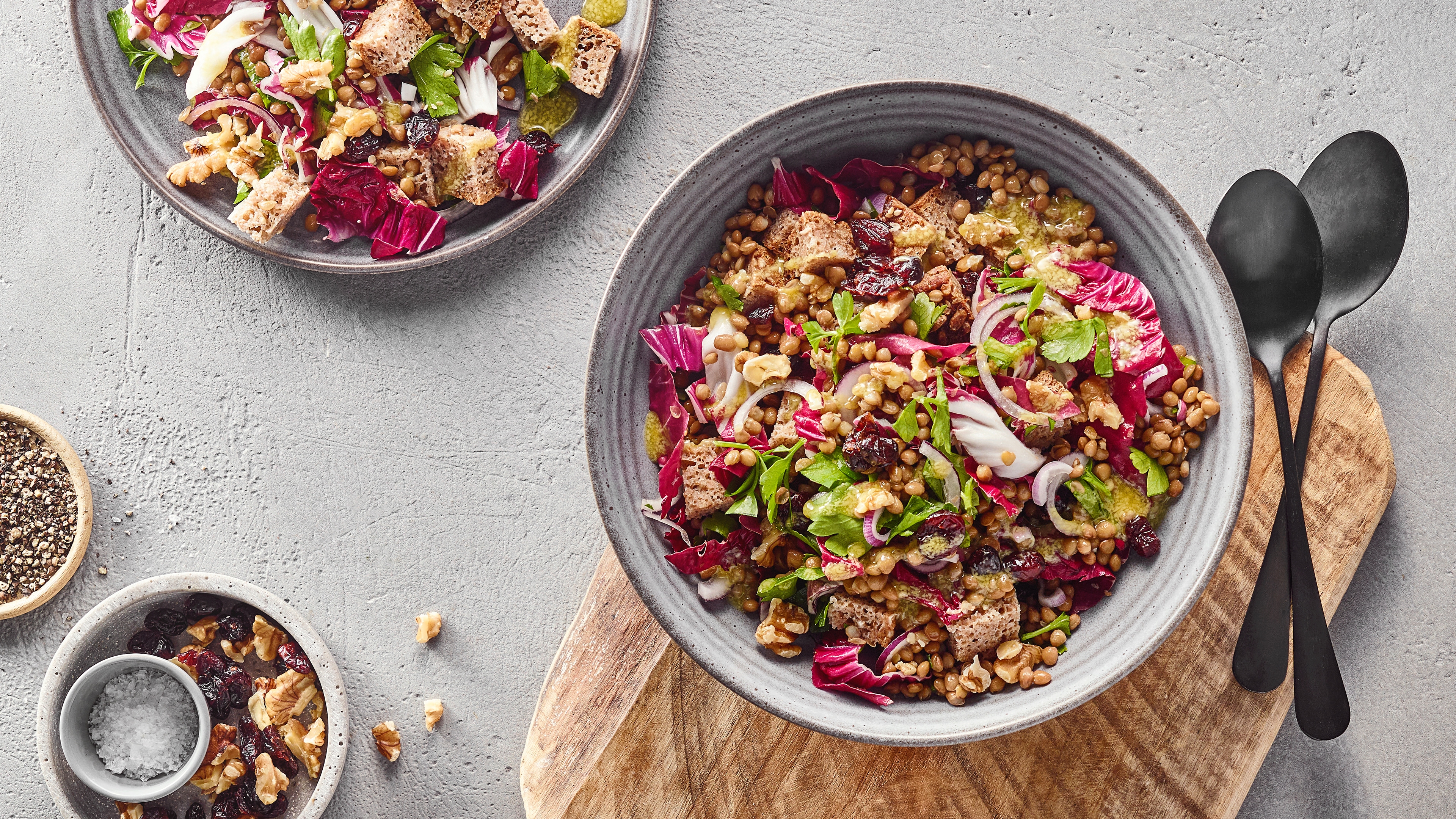 Große Schalen mit einem Salat aus Linsen, Brotstücken, roten Salatblättern und Zwiebeln