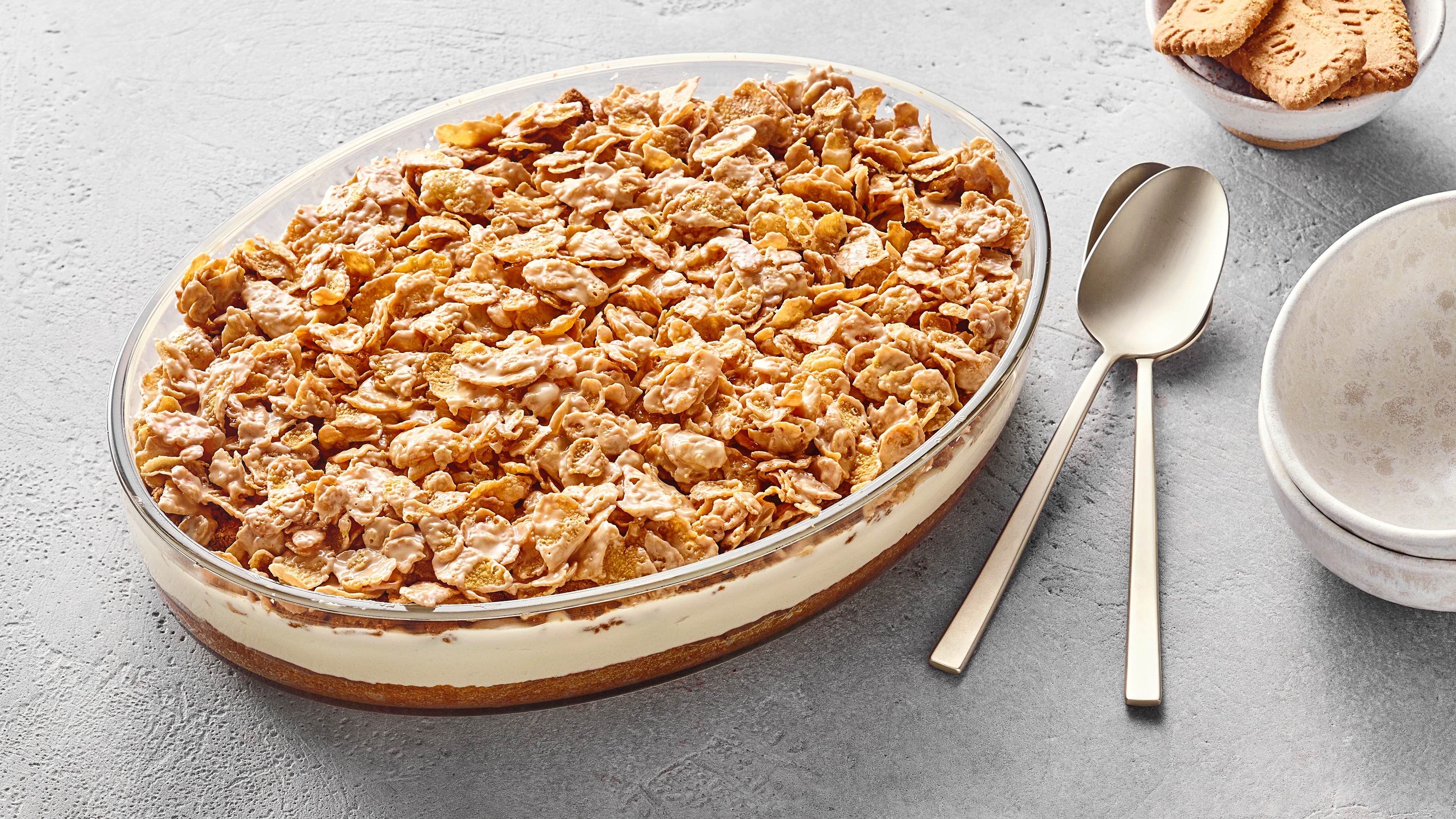 Schichtdessert aus zerbröselten Lotus‑Biscoff‑Keksen, cremiger Sahnefüllung und einem Keksboden in einer ovalen Glasform.