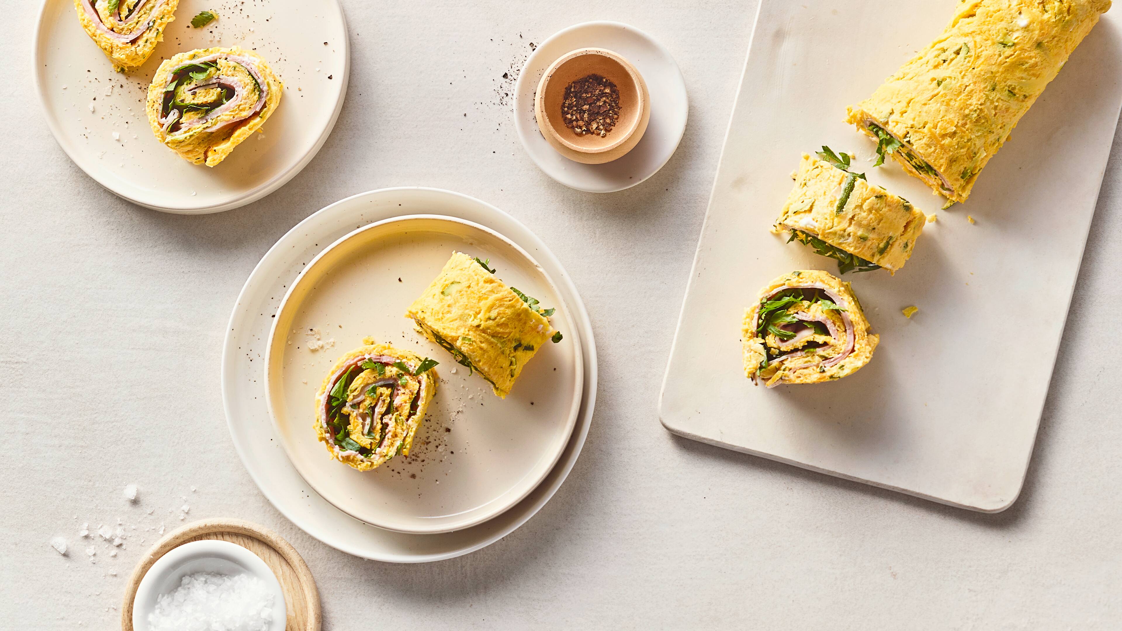 Rezept für Low Carb Gemüserolle Runde Teller mit geschnittenen Omlette-Rollen mit Schinken und Gemüse