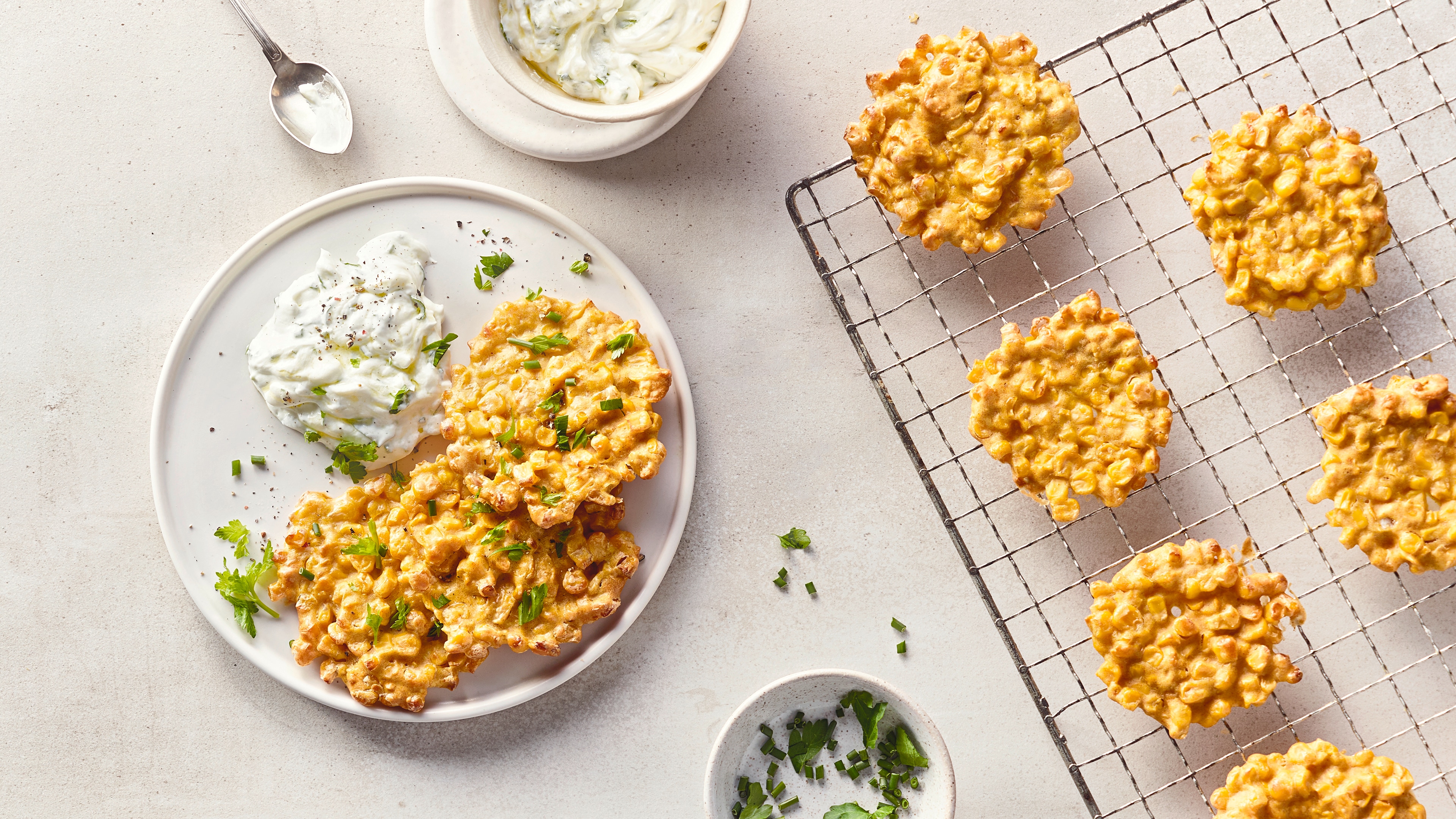 Rezept für Maistaler mit Kräuterdip Ein Teller mit knusprig gebackenen, runden Maistalern und einem cremigen Kräuterdip, getoppt mit frischem Schnittlauch
