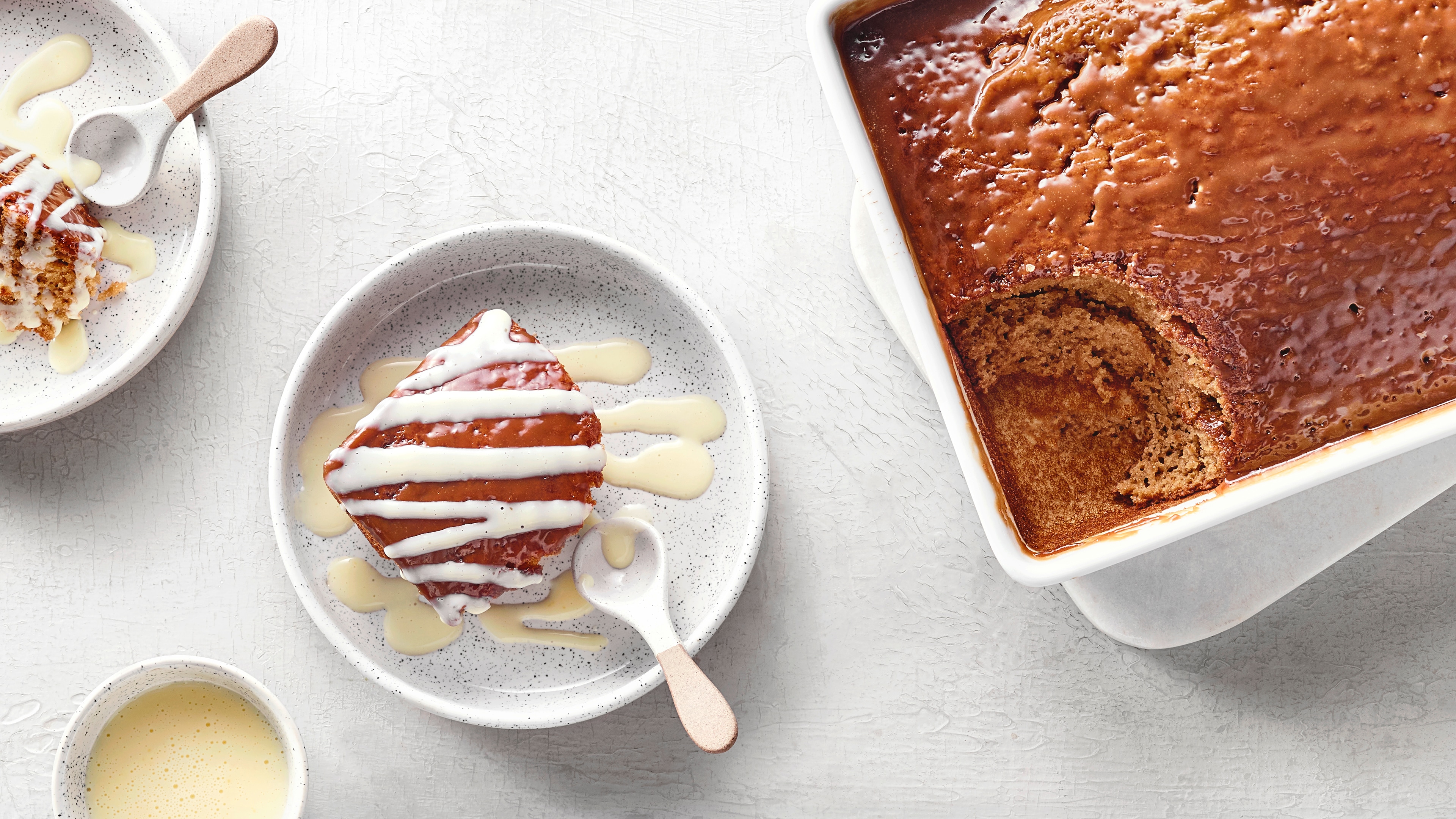 Schwammiges Schokokadendessert in rechteckiger Form. Links daneben wurde ein Stück herausgenommen und mit Vanillesauce serviert.