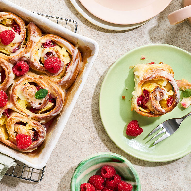 Auflaufform mit in Schneckenform gebackenen Teigstücken, dazu Himbeeren