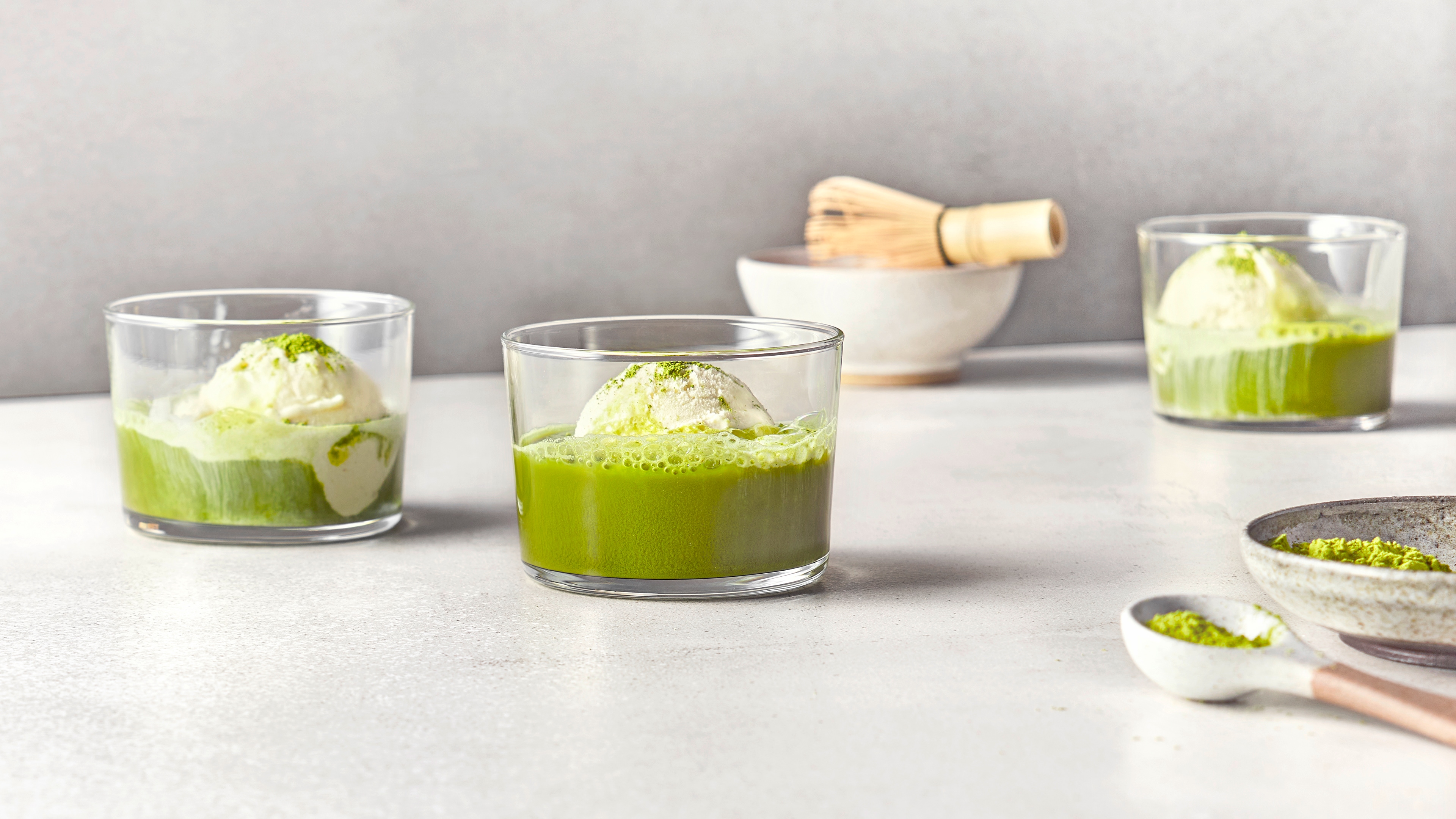 Drei Gläser mit grünem Matcha-Dessert und einer Kugel Vanilleeis.