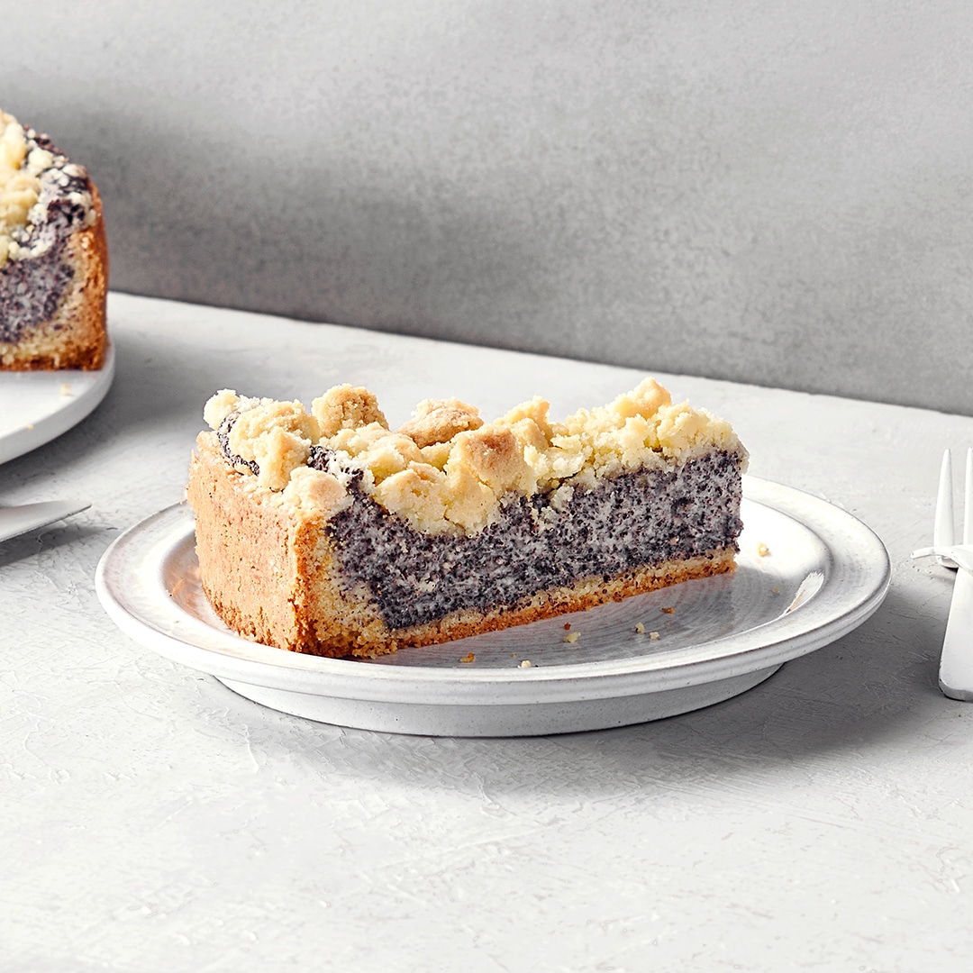 Teller mit einem Stück Streuselkuchen mit einer puddingartigen Mohnfüllung.