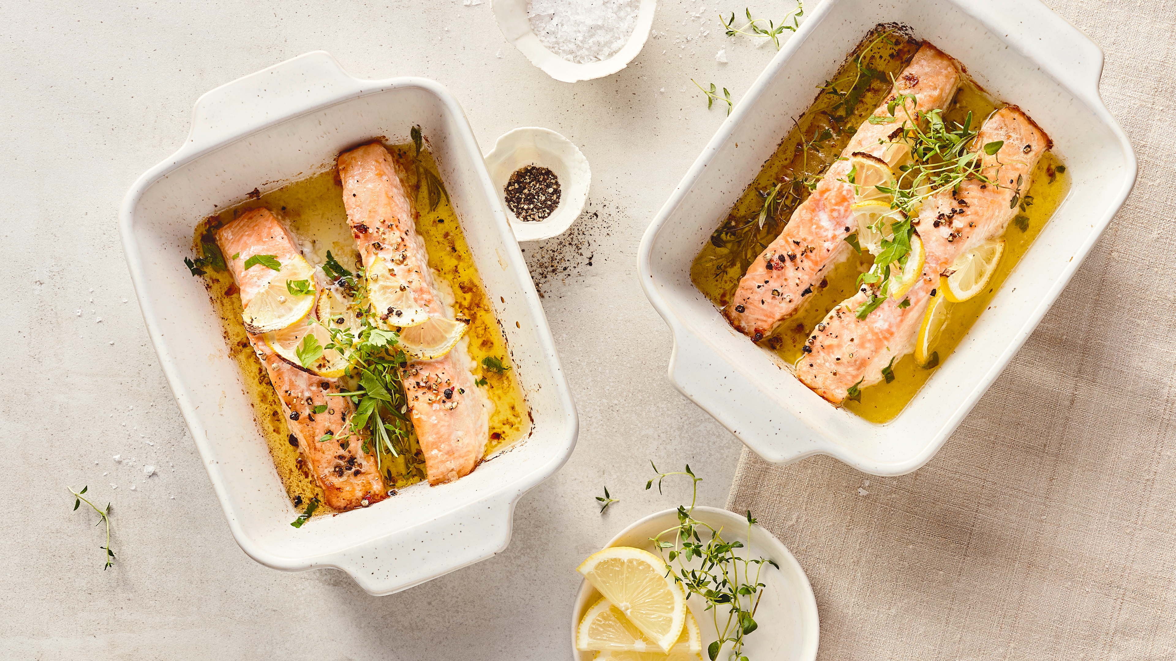 Rezept für Ofenlachs Kleine Auflaufformen mit gelbgold gebackenem Lachs in Öl, getoppt mit frischen Kräutern und Zitronenspalten