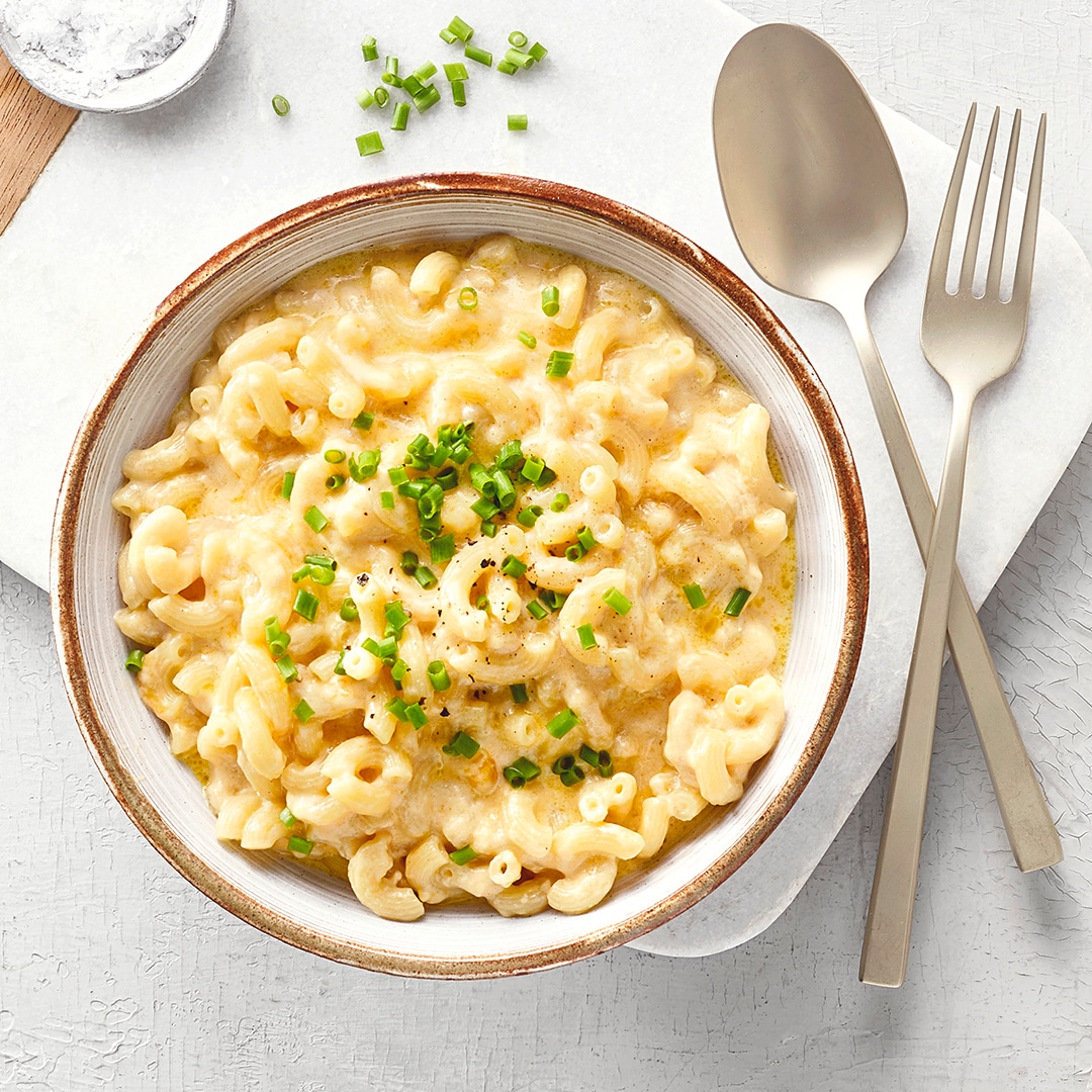 Große Schale mit Makkaroni und einer cremigen Sauce. Rechts daneben ein größerer Topf mit mehr Makkaroni.