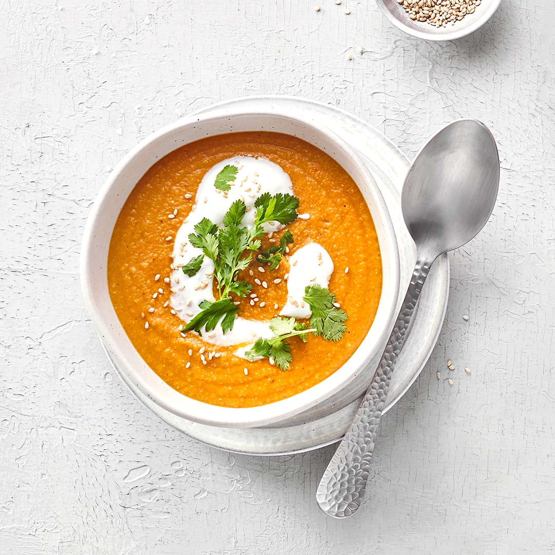 Zwei Schalen mit einer cremigen Linsensuppe, jeweils einem Klecks Joghurtcreme und Petersilie.