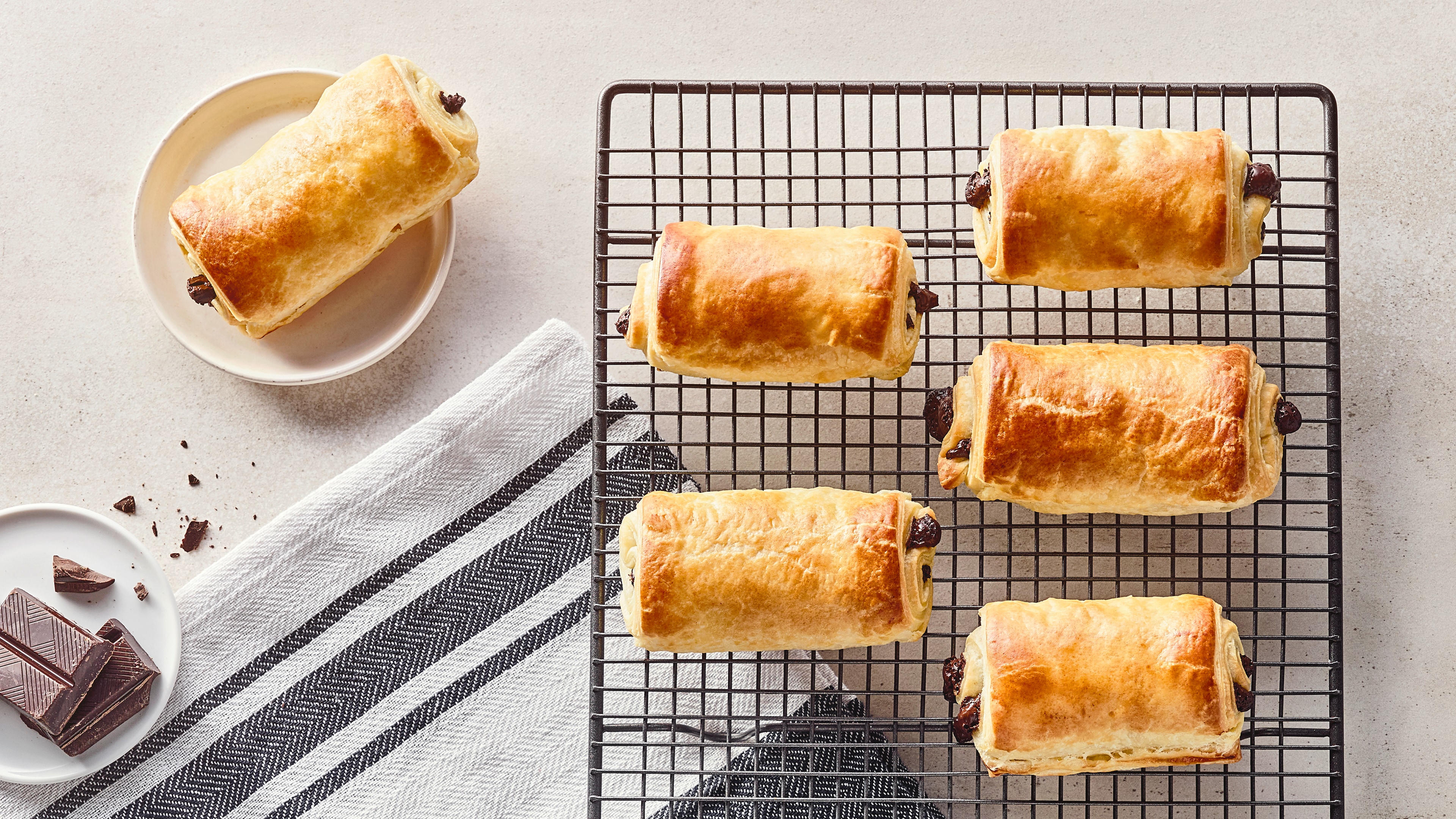 Rezept für Pain au Chocolat Längliche, gelbgold gebackene Teigwaren aus blättrigem Teig, gefüllt mit dunkler Zartbitterschokolade