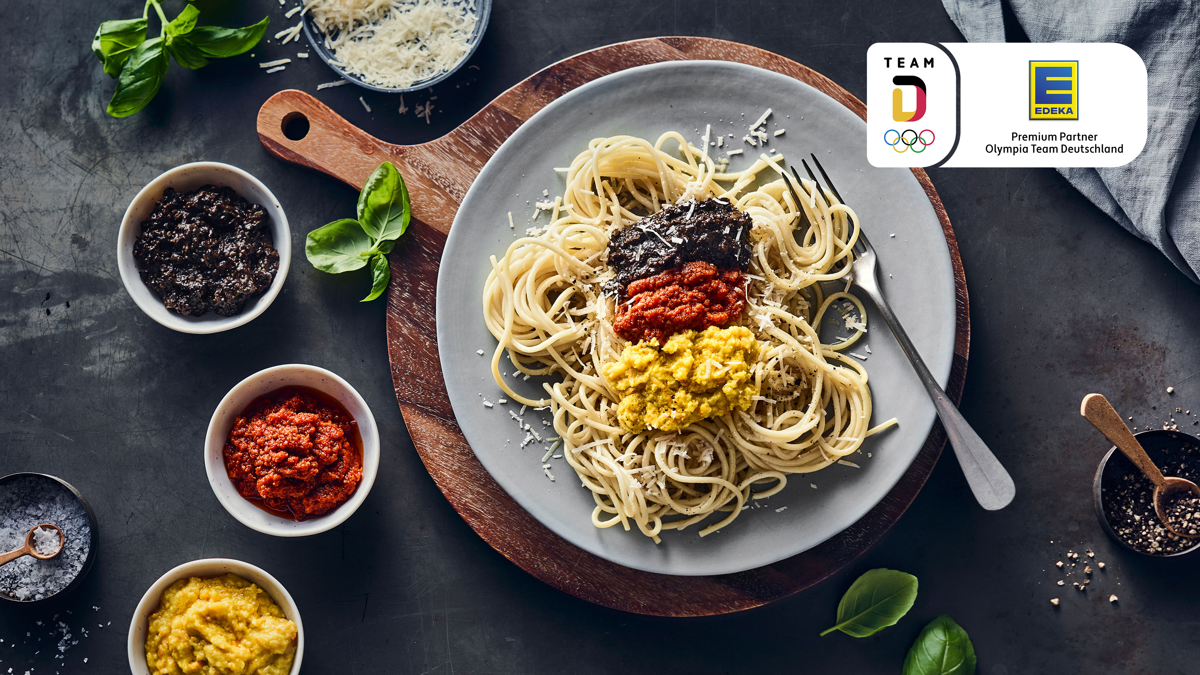 Rezept für Pasta mit dreierlei Pesto Teller mit Spaghetti und Pesto in drei Farben, daneben drei Schälchen mit den Pesto-Sorten.