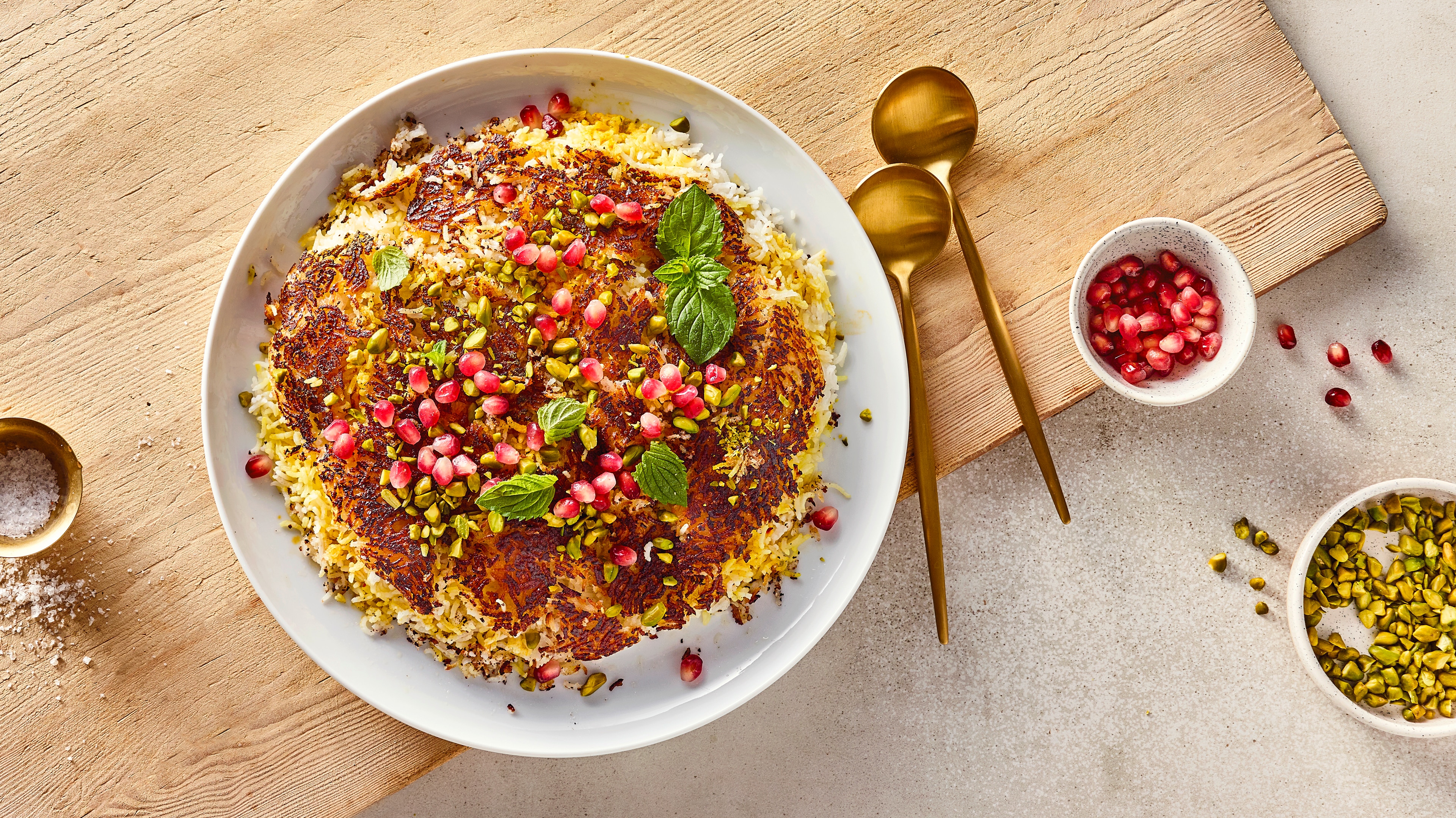 Rezept für persischen Reis Gebratener Reis, getoppt mit gehackten Pistazien, Granatapfelkernen und frischer Minze, auf einem großen Teller