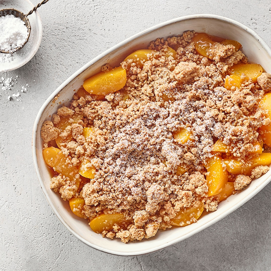 Auflaufform mit großen Pfirsichstücken und krümeligen Streuseln