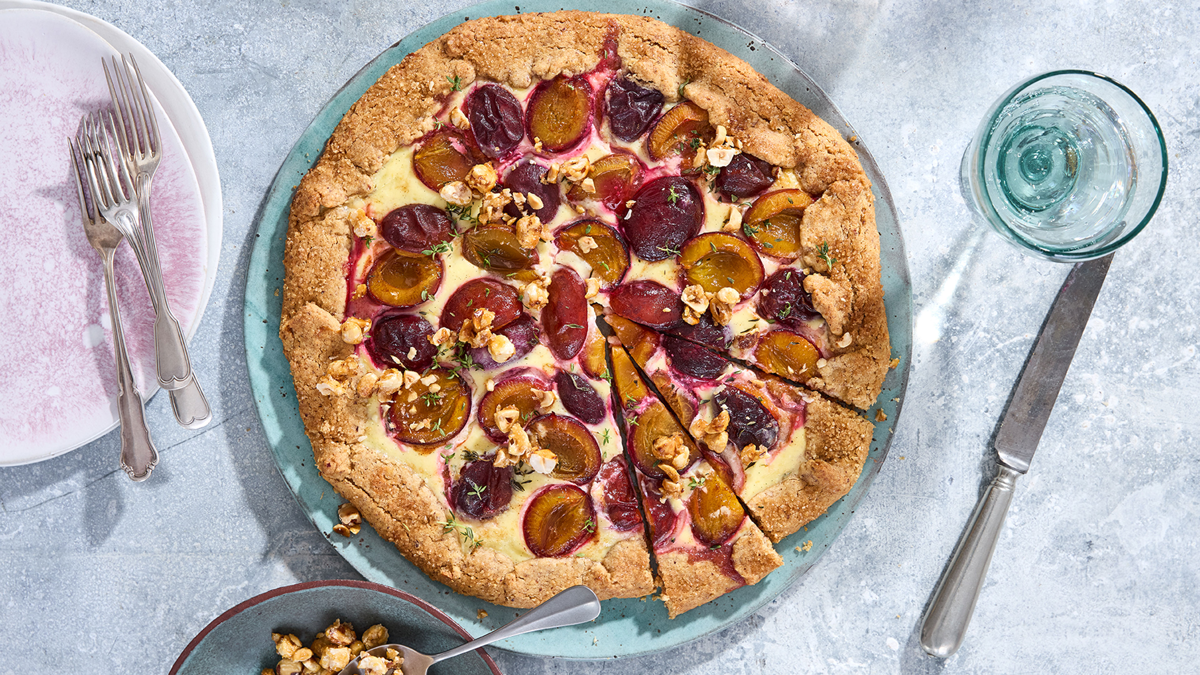 Ein Kuchen mit knusprigem Rand, Pflaumenhälften und Haselnusstücken