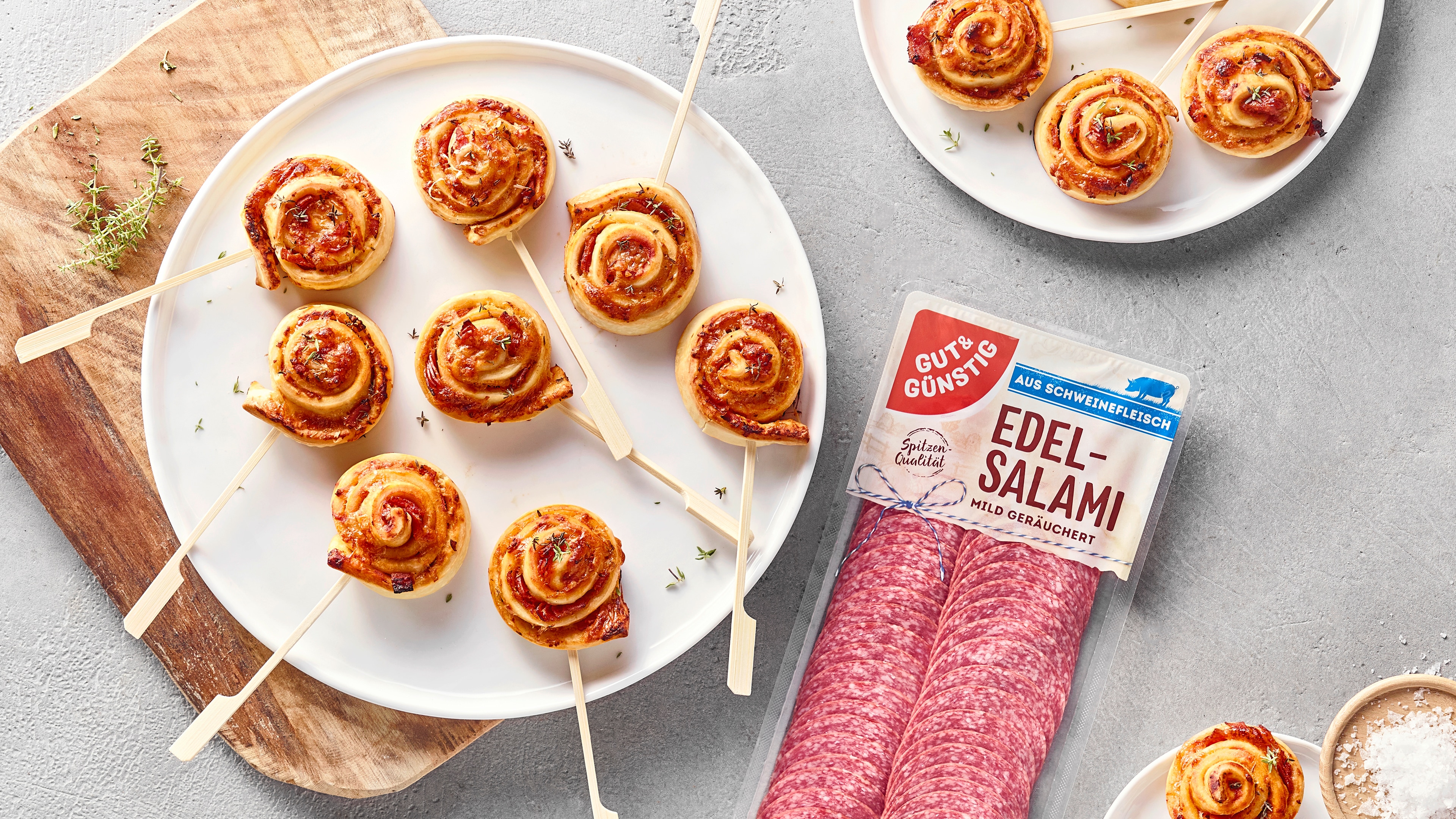 Blätterteig-Schnecken mit Tomatensauce und Salami am Stiel auf einem Servierteller, daneben GUT&GÜNSTIG Edel-Salami.