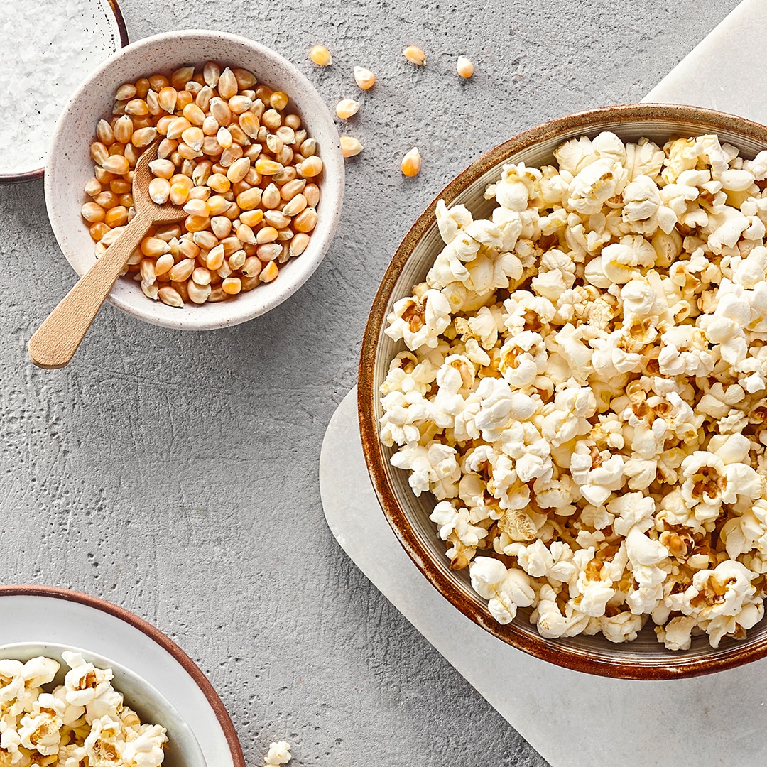 Große Schale mit Popcorn, daneben kleine Schale mit getrockneten Maiskörnern