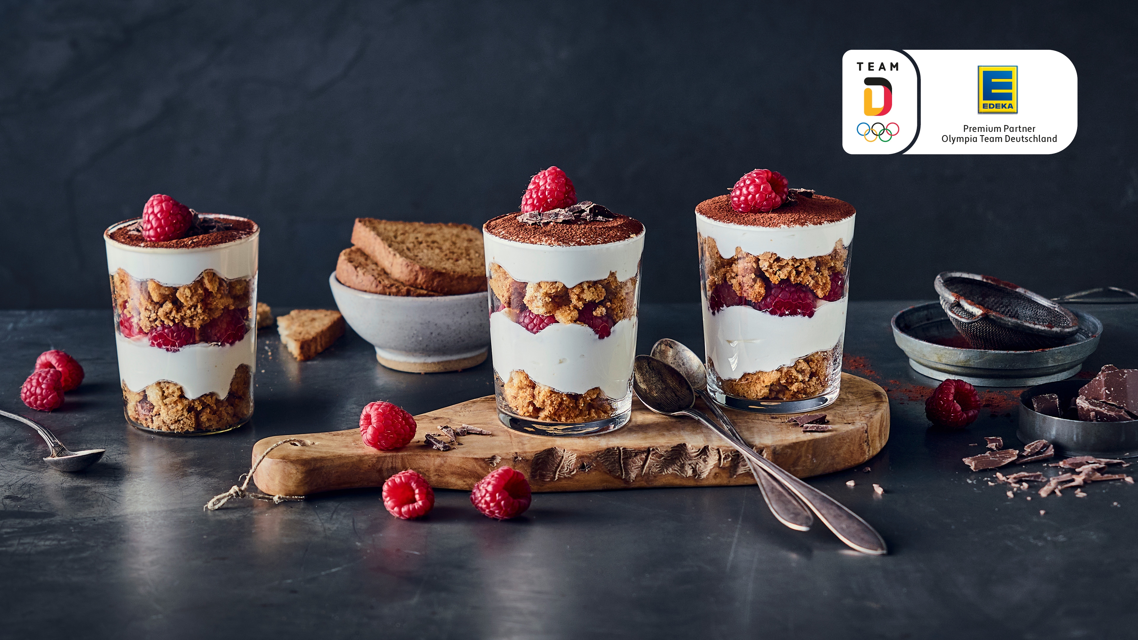 Rezept für Protein-Tiramisu 3 Gläser geschichtet mit heller Creme, dunklen Bröseln und Himbeeren
