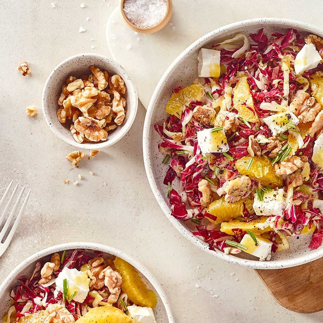 Eine Schale mit Radicchio, Orange, Ziegenkäsewürfel und Walnüssen, in Öl, getoppt mit frischem Rosmarin