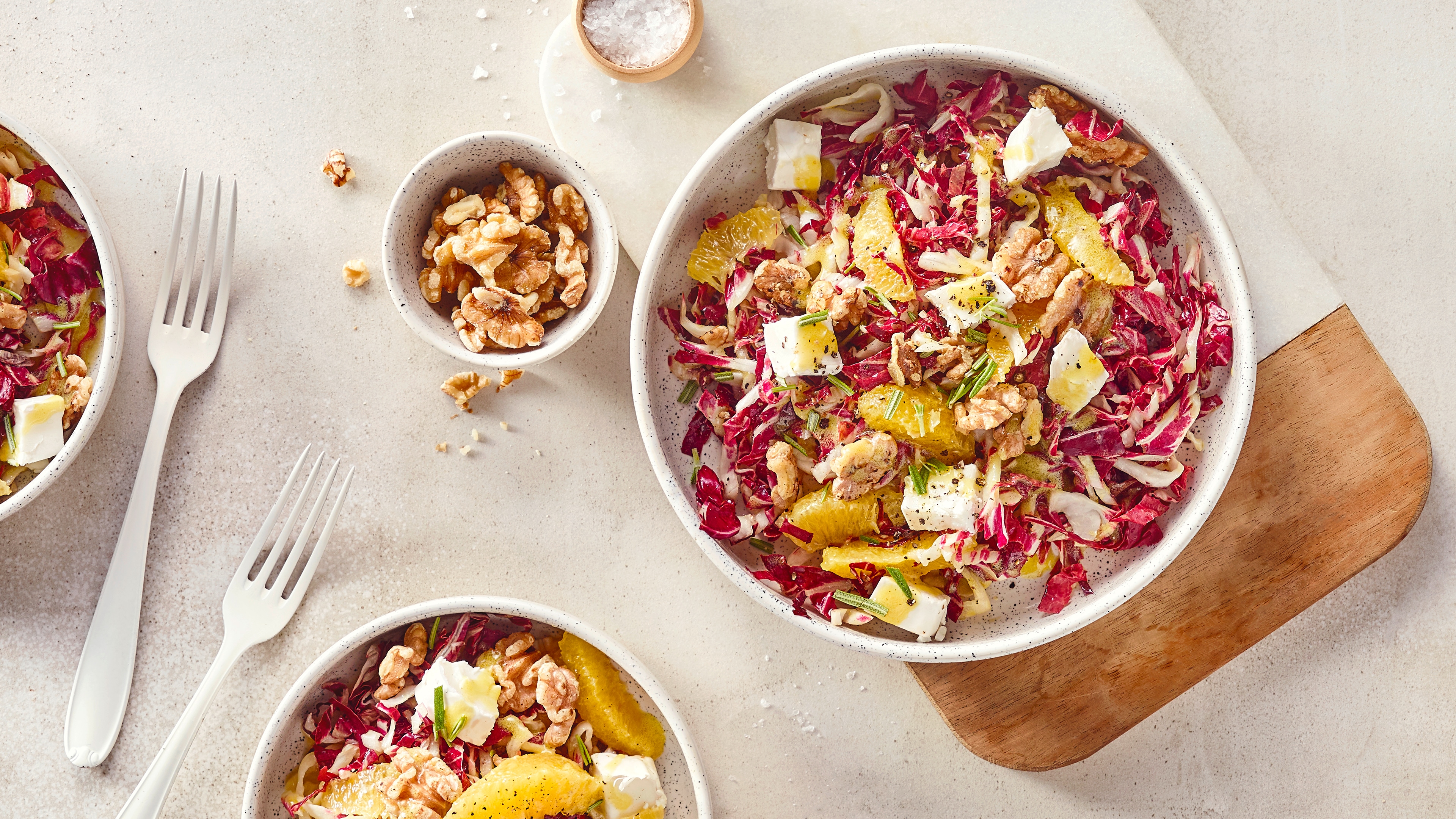 Rezept für Radicchio Salat Eine Schale mit Radicchio, Orange, Ziegenkäsewürfel und Walnüssen, in Öl, getoppt mit frischem Rosmarin