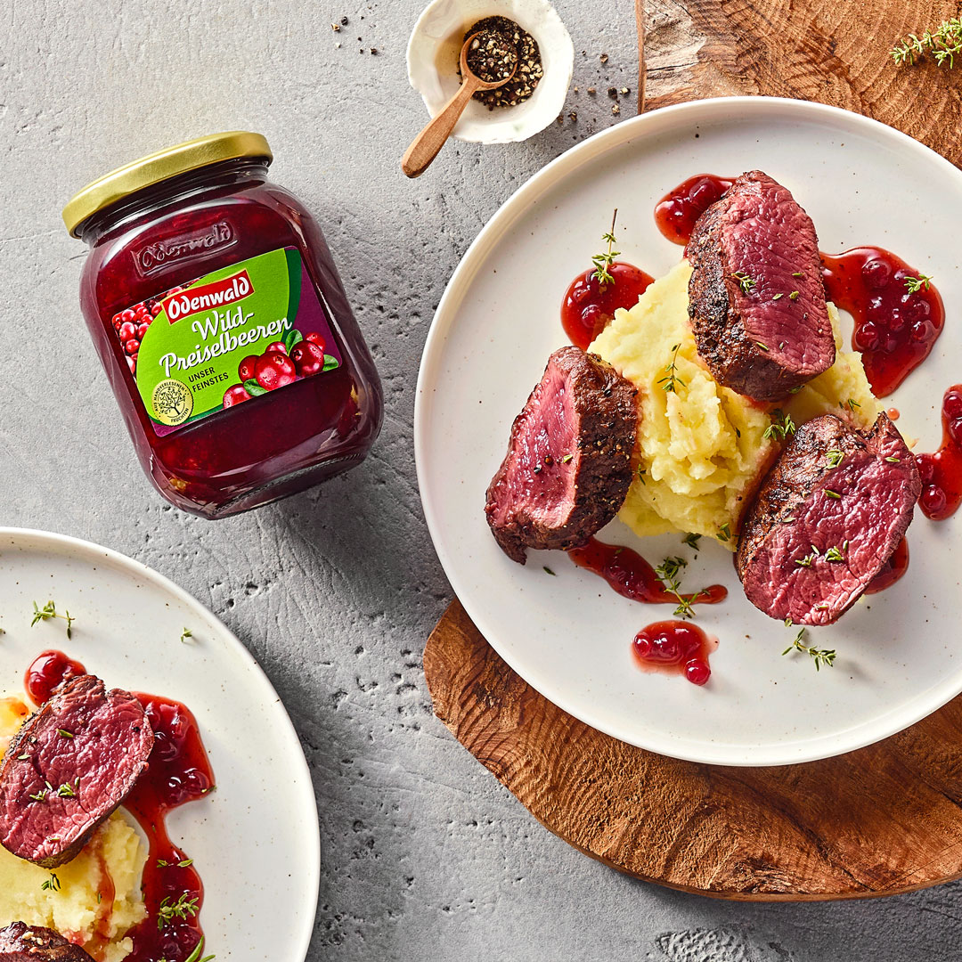 Teller mit Kartoffelpüree und Fleisch Medaillons mit Preiselbeersauce, daneben Odenwald Wild-Preiselbeeren
