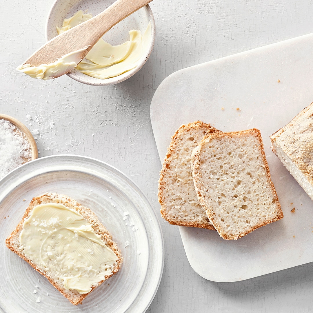 Helles, aufgeschnittenes Brot, daneben eine Scheibe mit Butter und Salz.