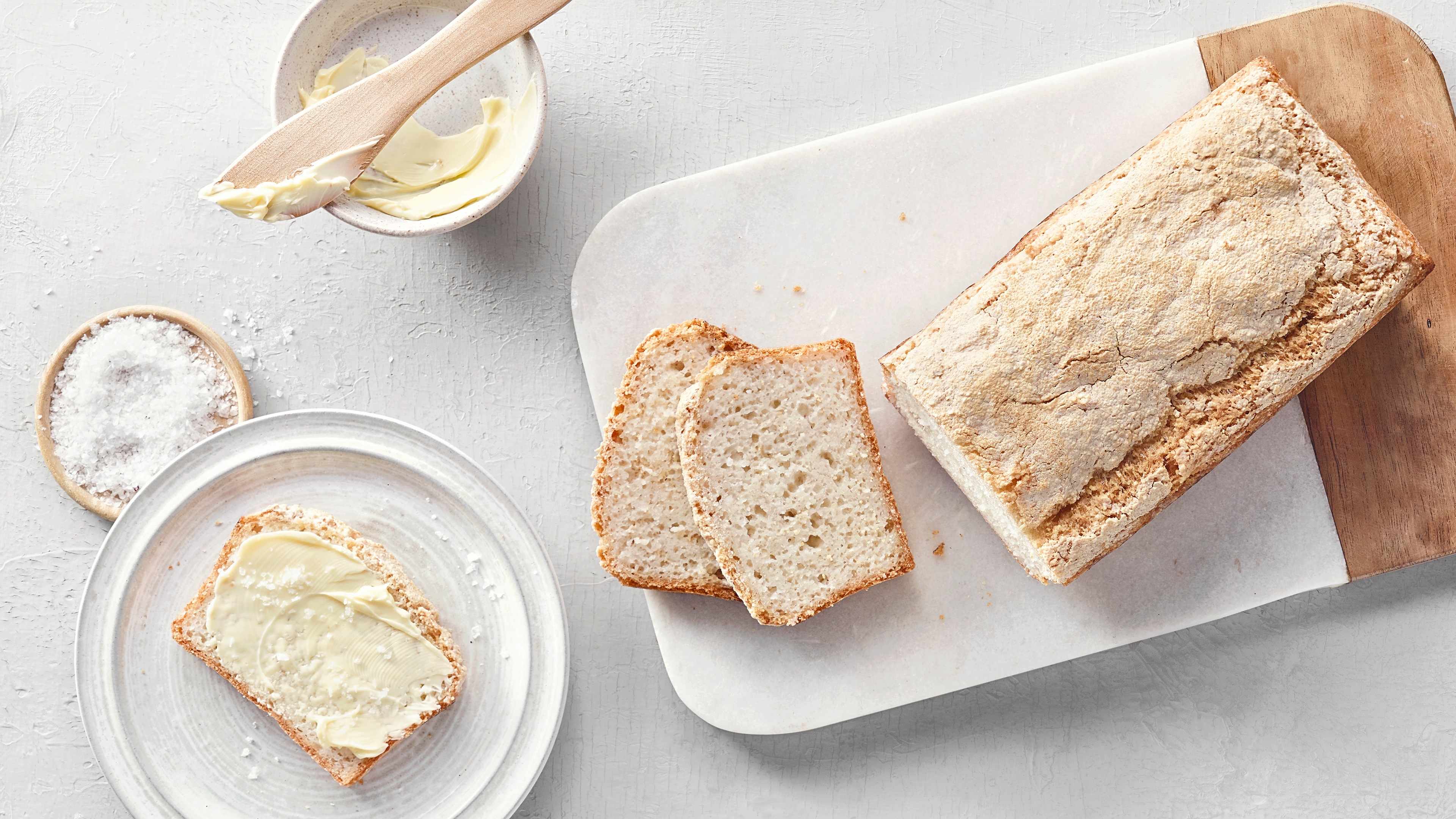 Helles, aufgeschnittenes Brot, daneben eine Scheibe mit Butter und Salz.