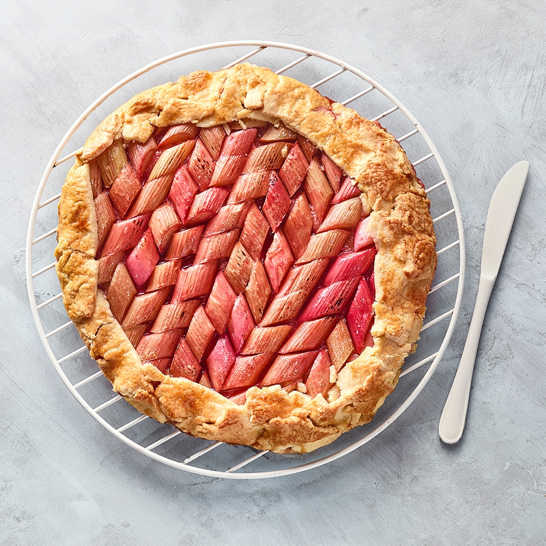 Rundes großes Gebäck auf Gitter mit Rhabarberstücken und Teigumrandung