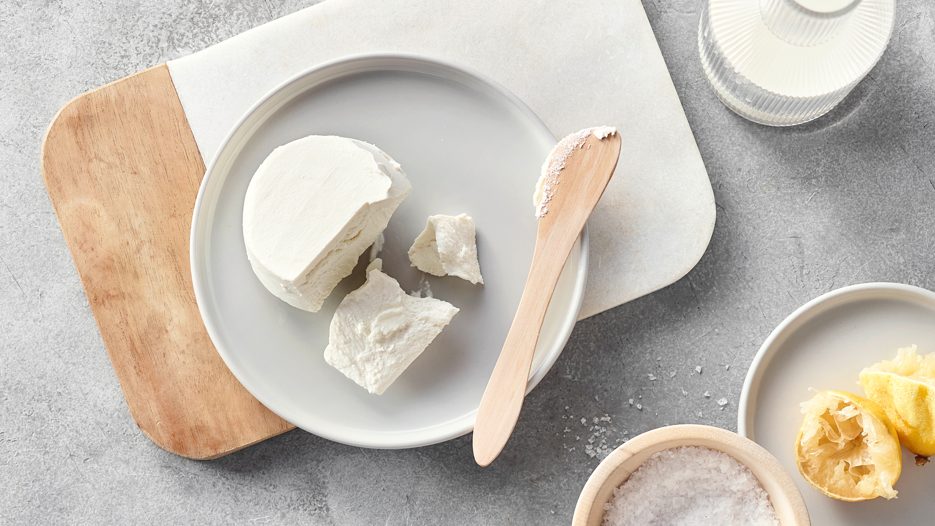 Rezept für selbst gemachtes Ricotta Ein rundes Stück fester, weißer, homogener Frischkäse, auf einem runden Keramikteller