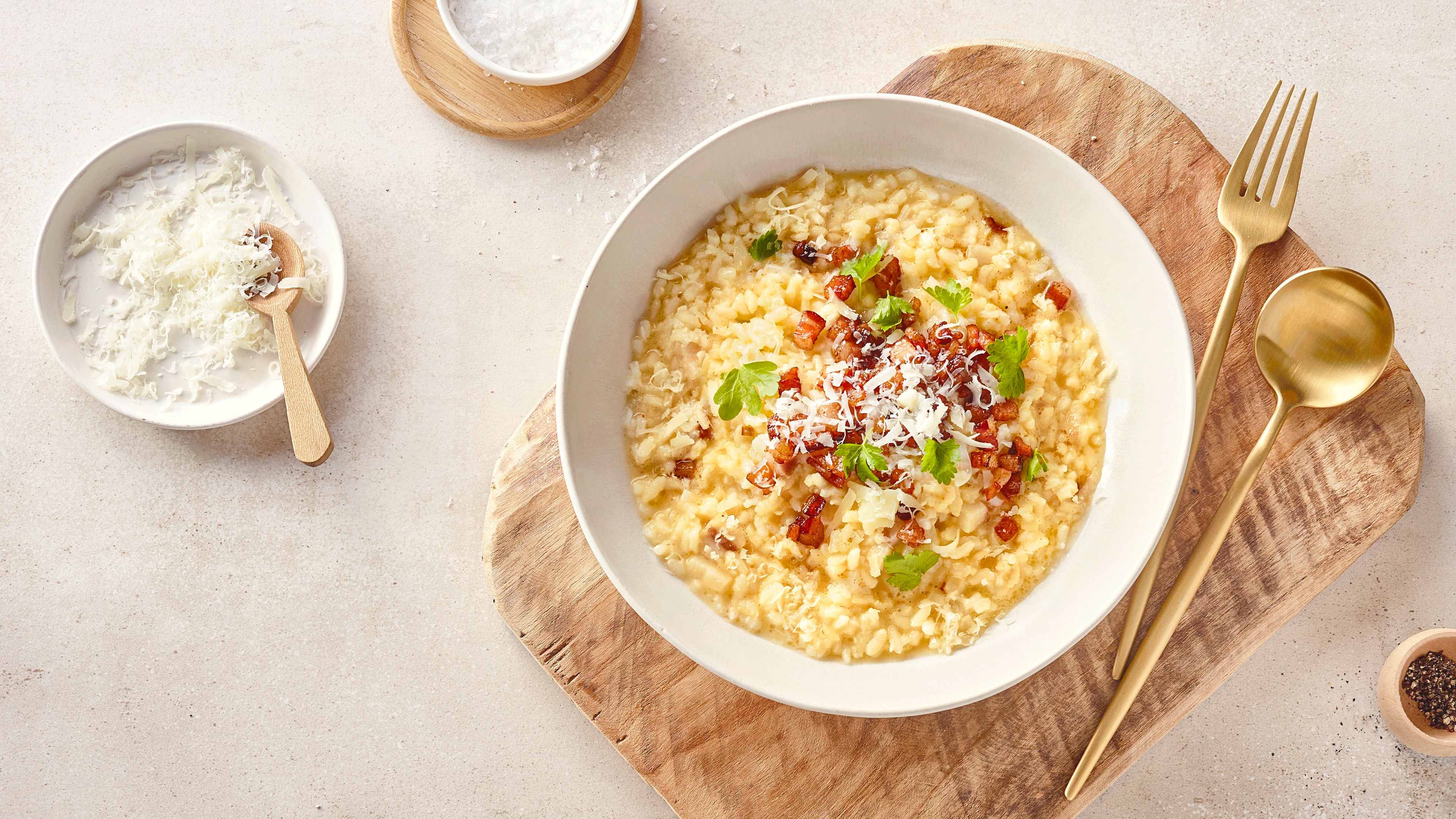 Eine Schale mit cremigem Risotto-Reis, garniert mit Schinkenwürfeln, geriebenem Käse und frischer Petersilie