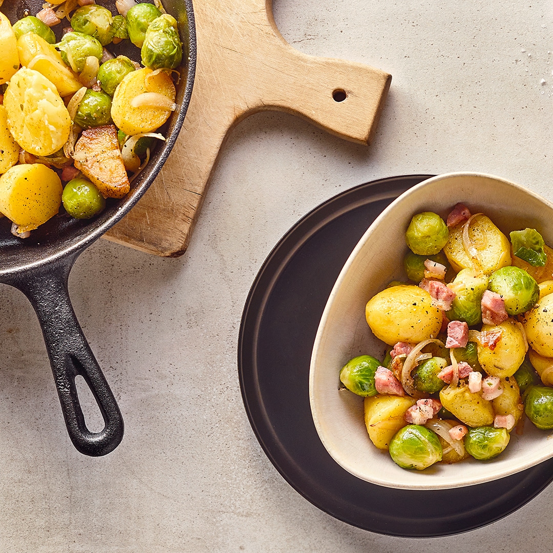 Keramikschalen mit Kartoffelstücken, Rosenkohl und Zwiebeln, getoppt mit Speckwürfeln