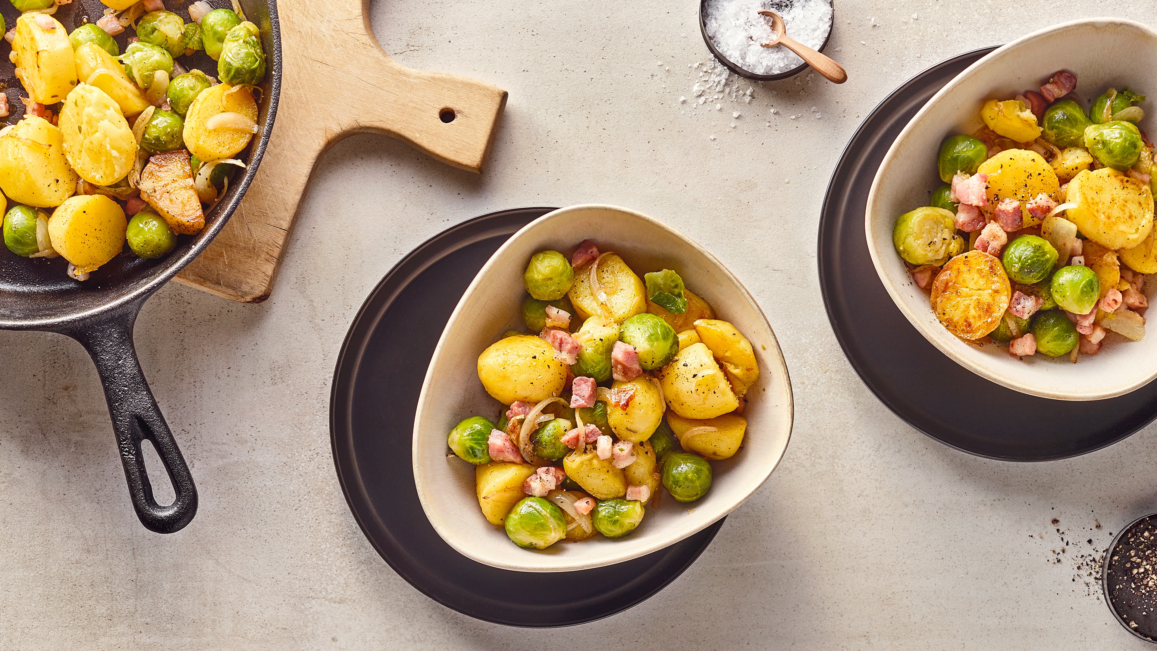 Keramikschalen mit Kartoffelstücken, Rosenkohl und Zwiebeln, getoppt mit Speckwürfeln