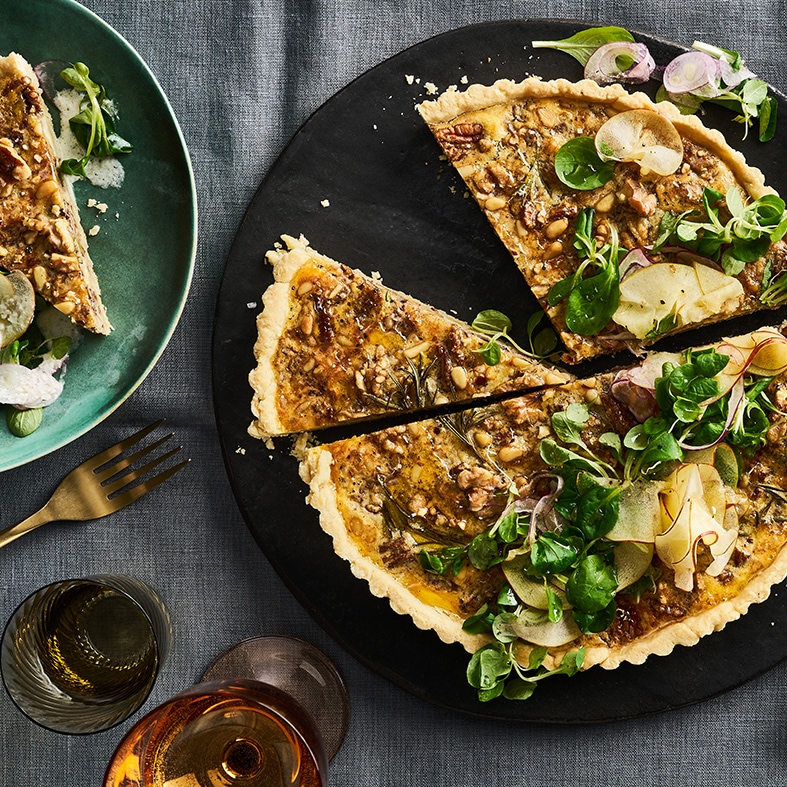 Knusprig gebackene Tarte mit Nüssen und Feldsalat auf großem Teller