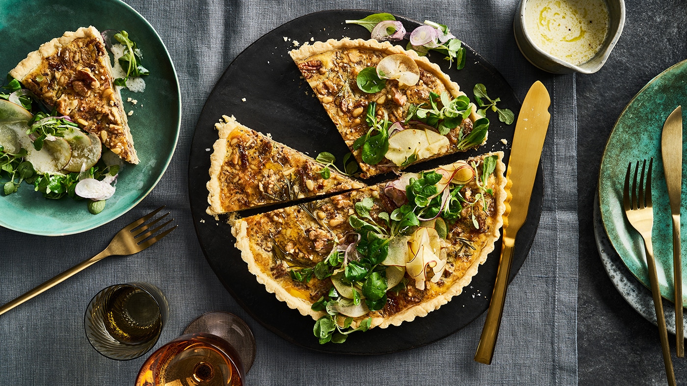 Knusprig gebackene Tarte mit Nüssen und Feldsalat auf großem Teller