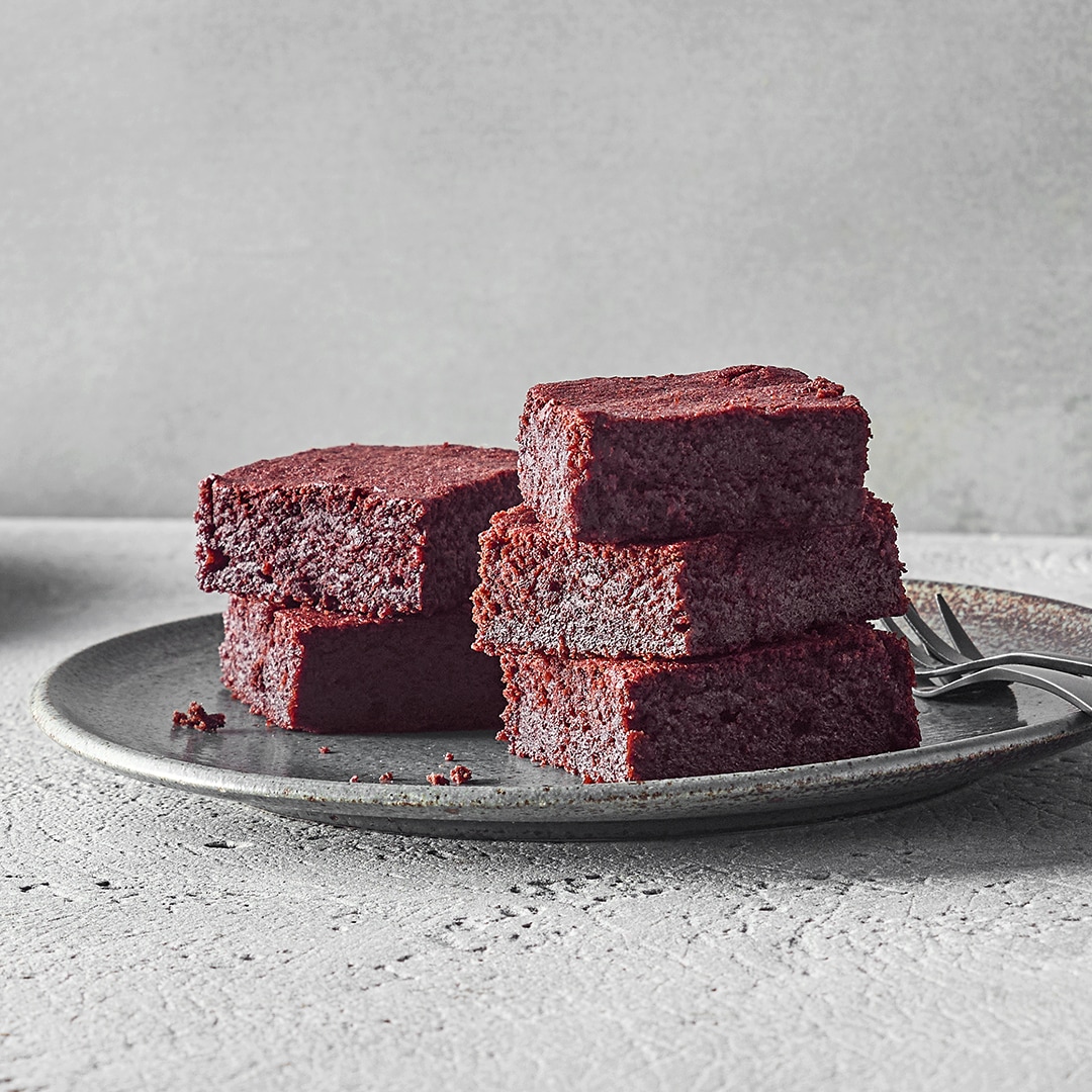 Ein Teller mit saftigen Brownies, daneben ein paar Krümel.