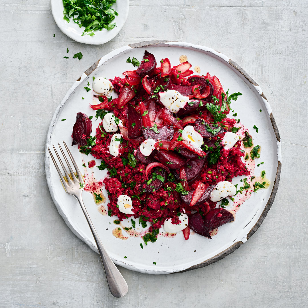 Roter Salat mit Roter Bete, Bulgur und kleinen Mozzarella-Kugeln auf einem weißen Teller, garniert mit frischen Kräutern.
