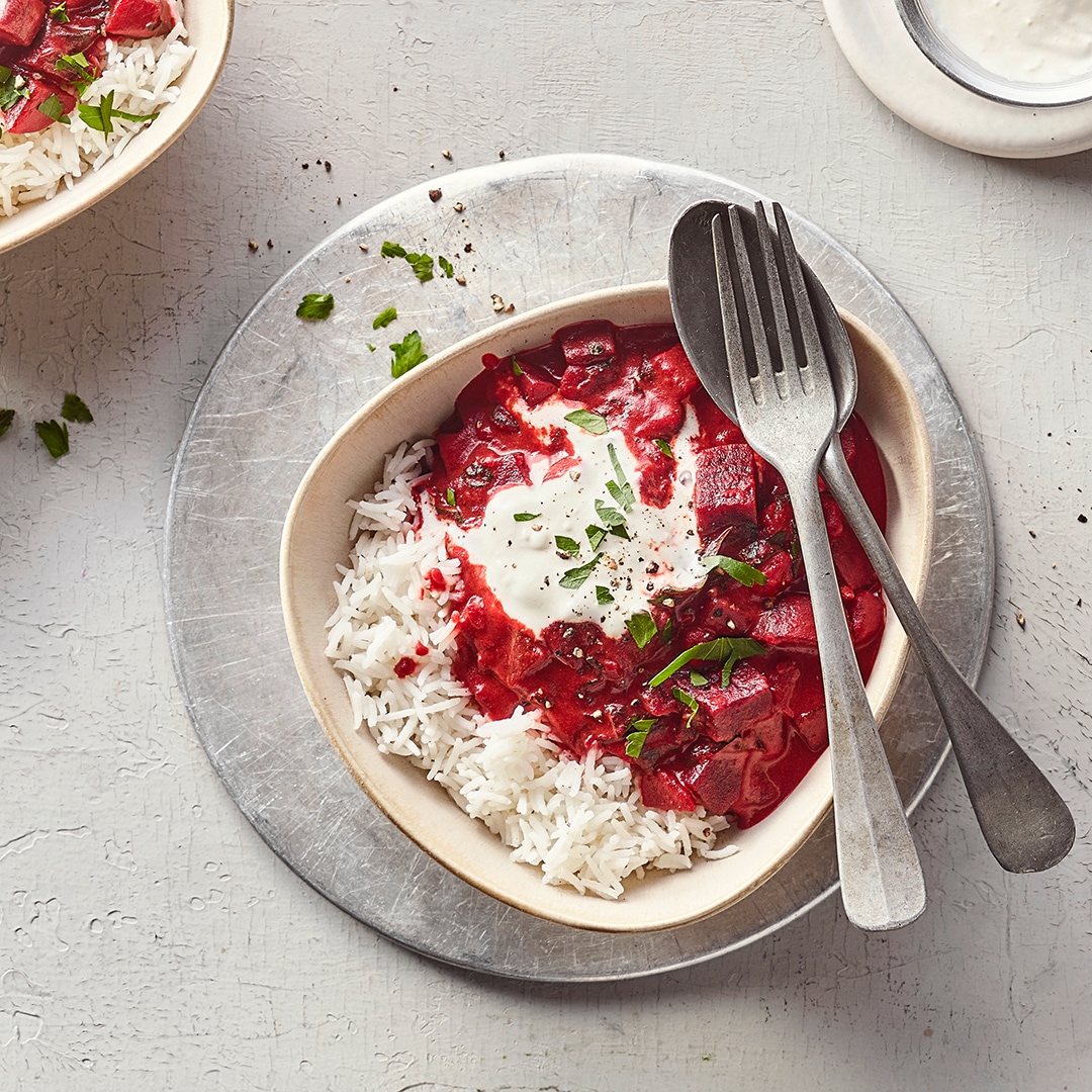 Eine Schale mit Reis und einer roten Sauce mit Rote-Bete-Stückchen, getoppt mit einem Klecks weißer Creme