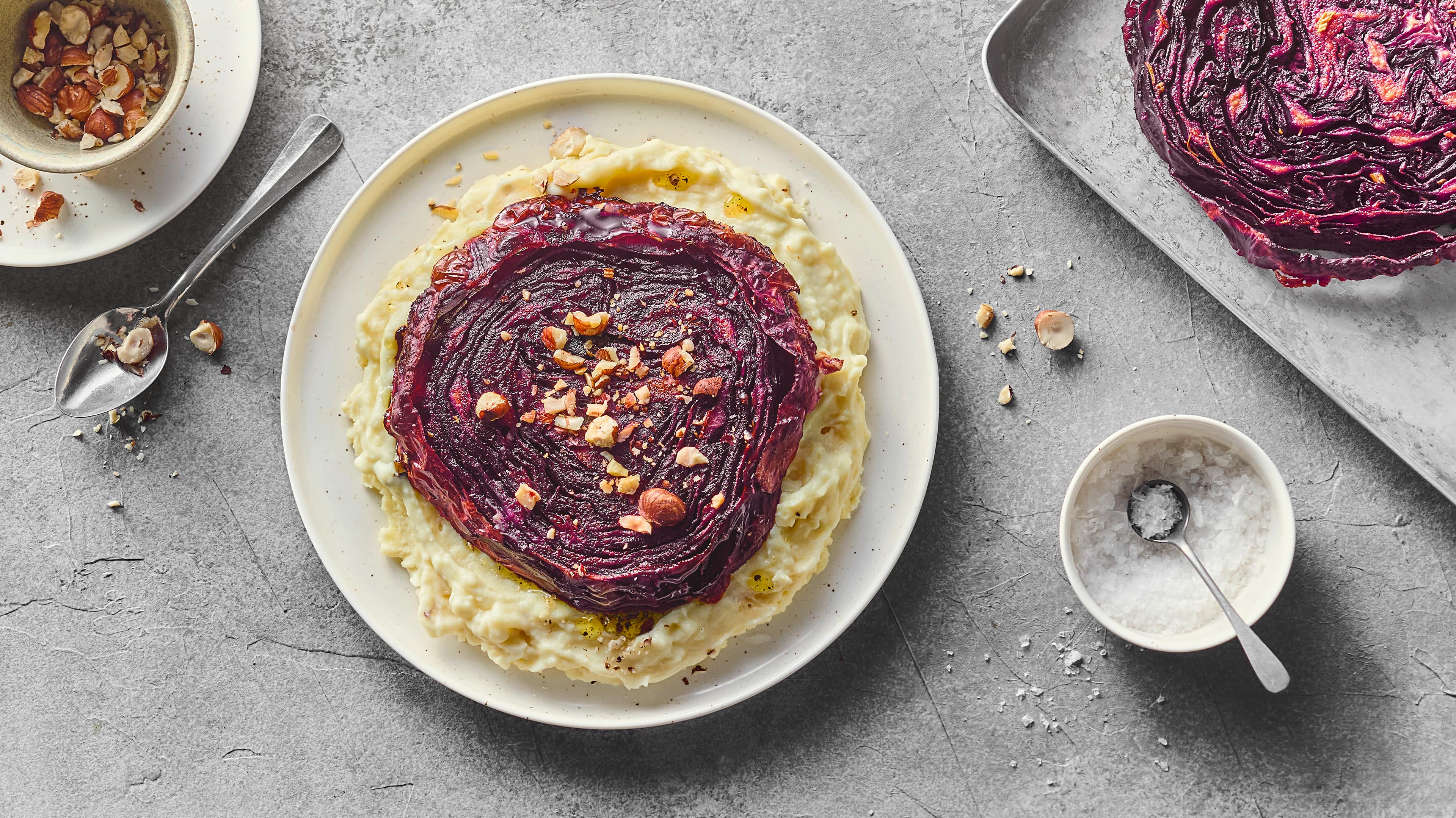 Rezept für Rotkohl Steaks Ein saftiges Rotkohl-Steak, gebettet auf cremigem Kartoffelstampf, getoppt mit Haselnüssen, auf einem runden Teller