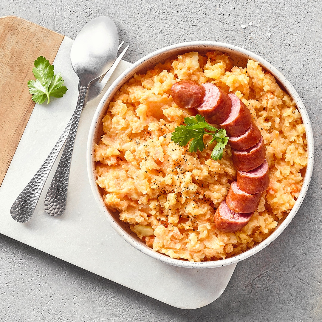 Schale mit grobem Mus, darauf Wurstscheiben